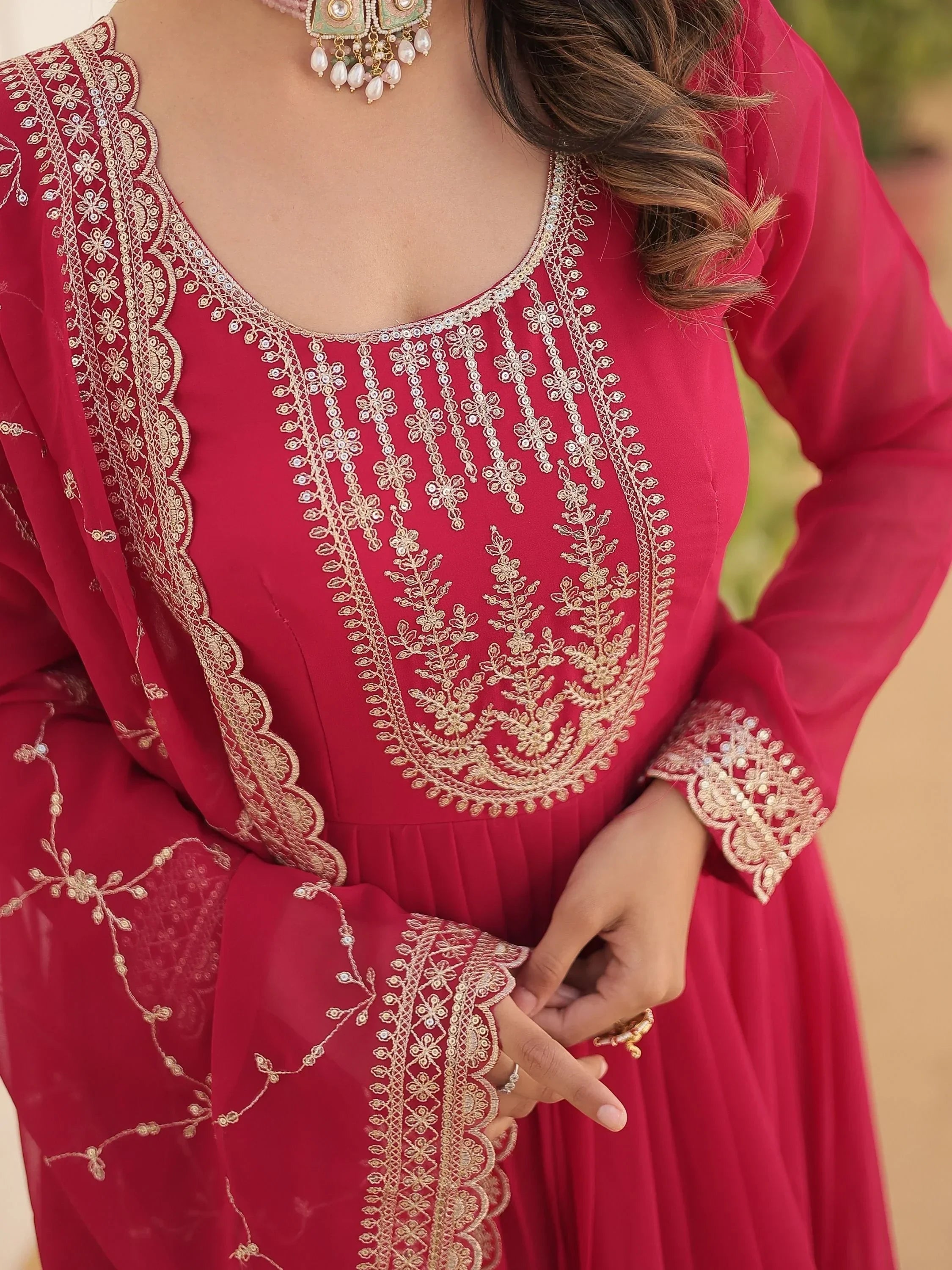 Pink Indian ethnic gown with gold embroidery, sheer dupatta, and traditional jewelry