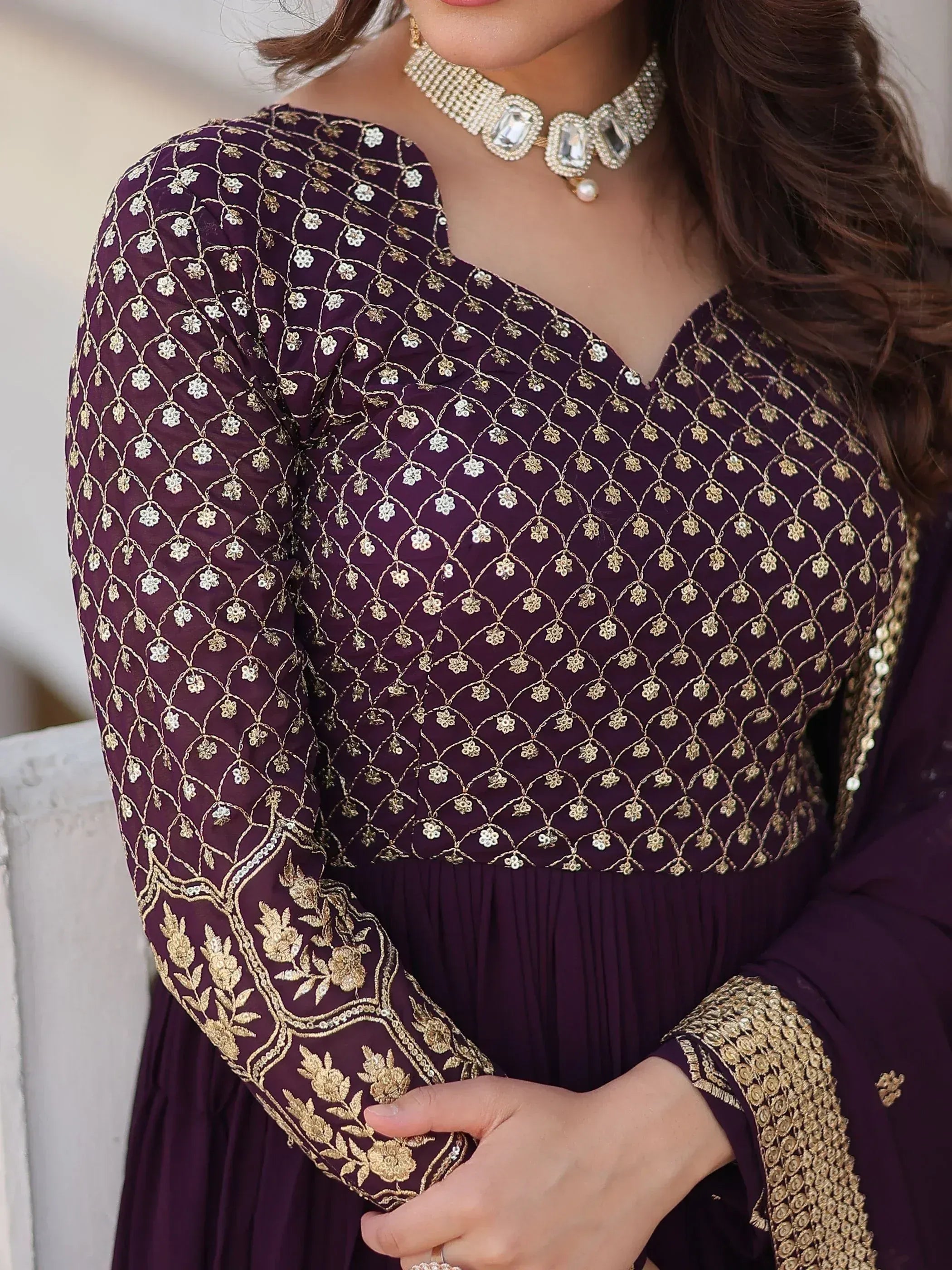 Purple ethnic gown with gold floral embroidery and embellished neckline, paired with statement jewelry