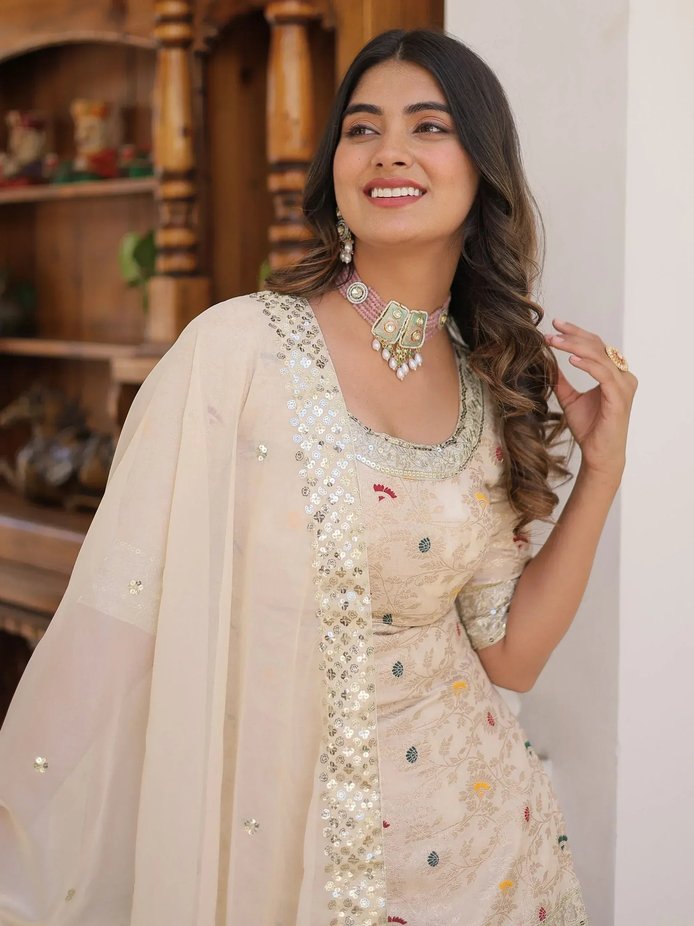 Woman in elegant cream ethnic gown with floral embroidery and sequin dupatta, perfect for Indian occasions