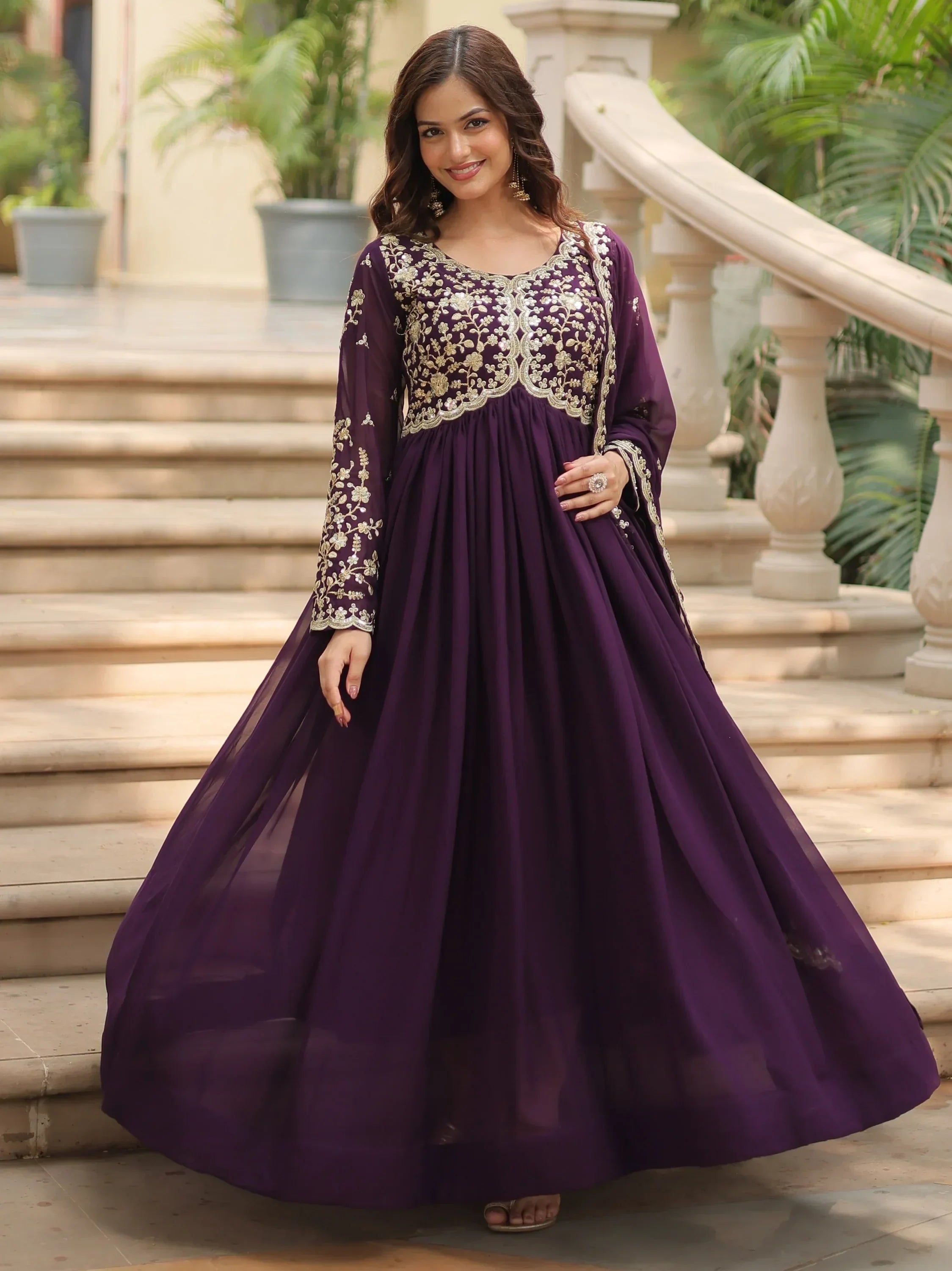 Woman wearing a purple embroidered ethnic gown with gold floral details, standing outdoors
