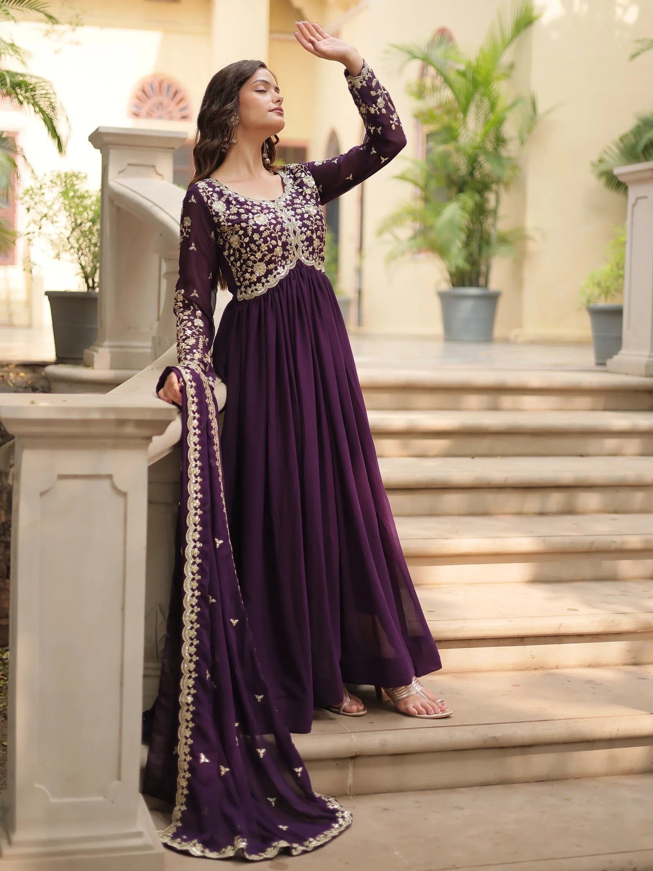Woman wearing purple embroidered ethnic gown with dupatta on outdoor steps