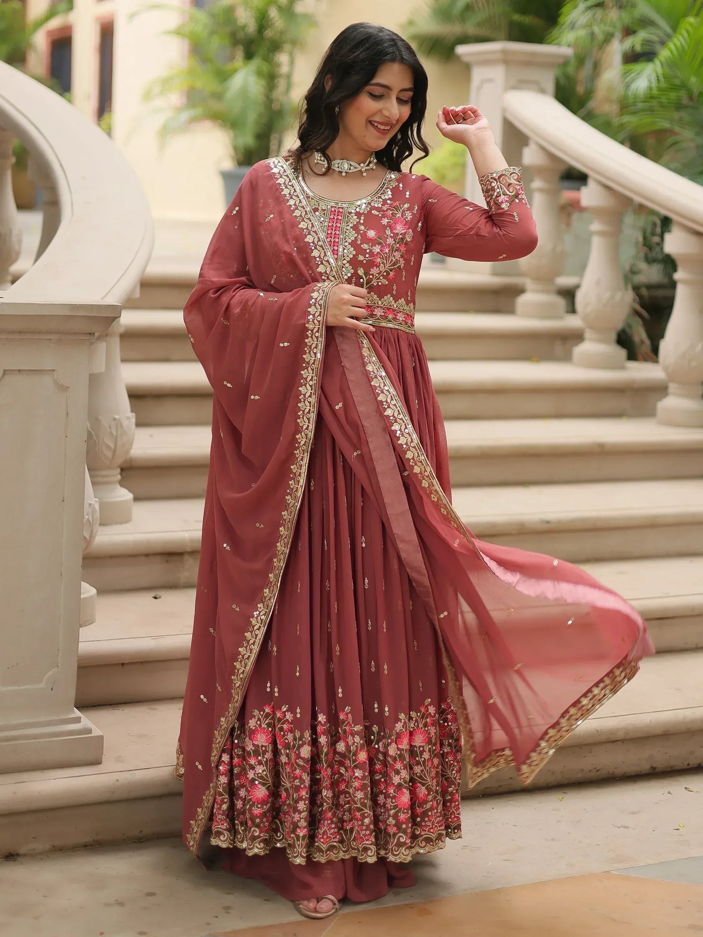 Elegant maroon ethnic gown with floral embroidery and gold detailing, perfect for Indian celebrations.