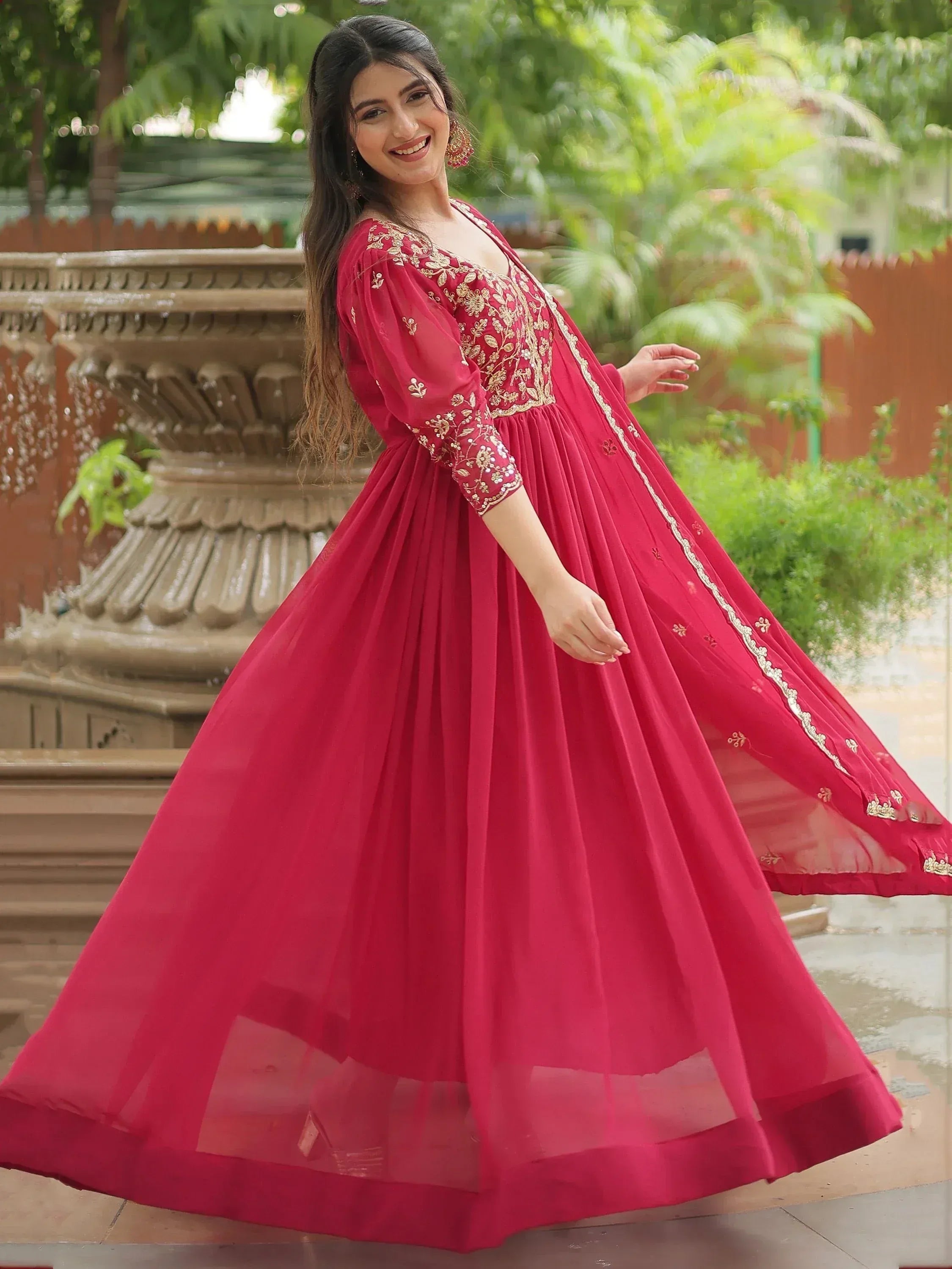 Red ethnic gown with gold embroidery, flared skirt, and sheer overlay for festive occasions
