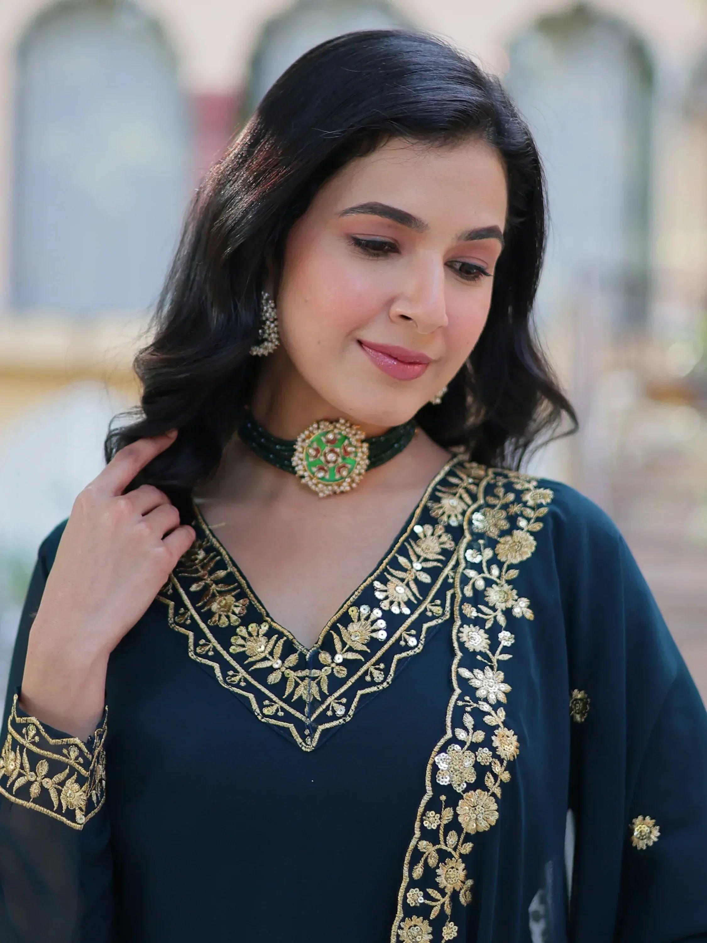 Woman in dark green ethnic kurti with gold floral embroidery and matching choker necklace