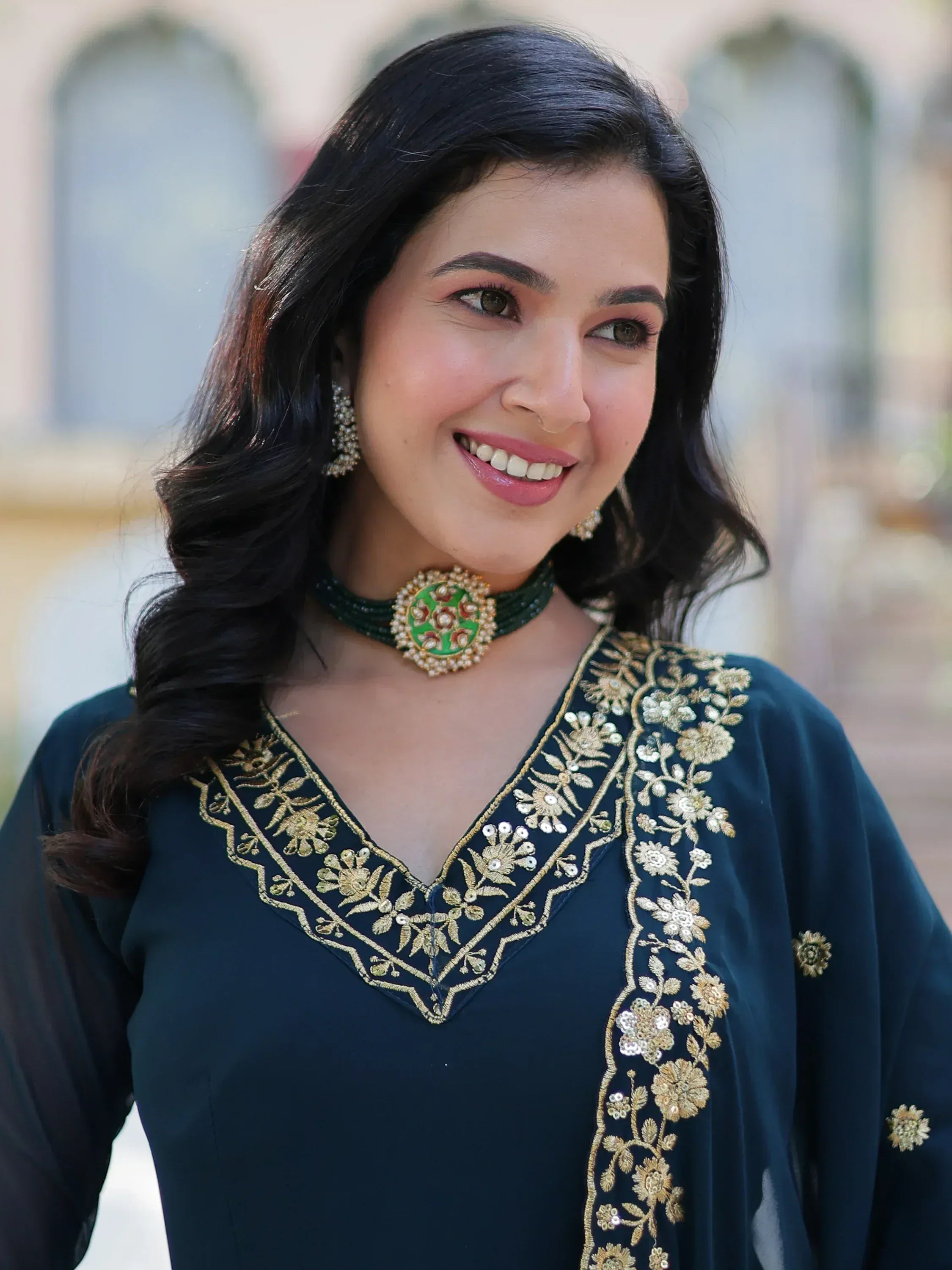 Woman in dark green embroidered ethnic kurti with gold floral work and matching choker necklace