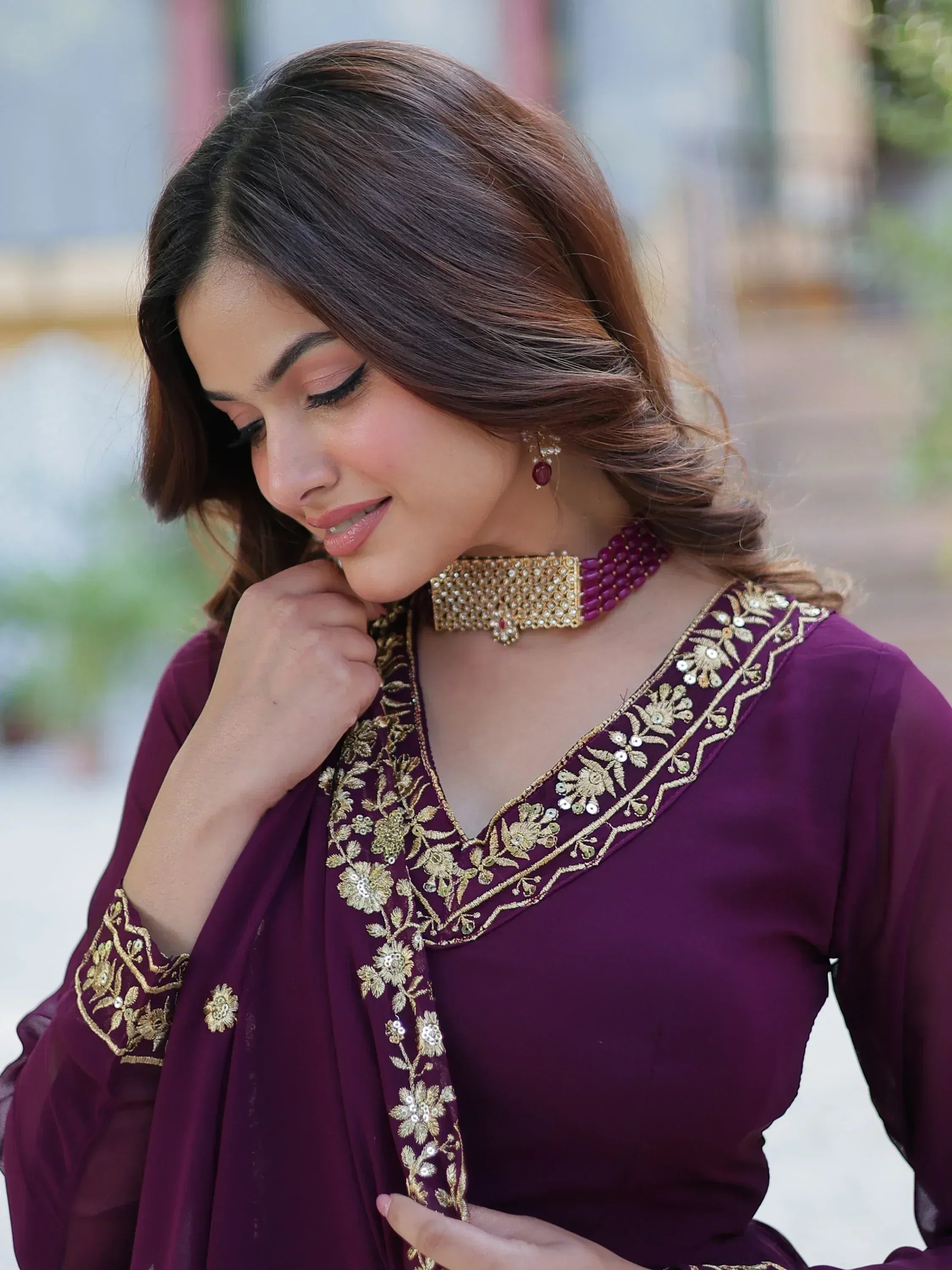 Woman in purple ethnic wear with gold embroidery, floral detailing, and matching jewelry for Indian occasions
