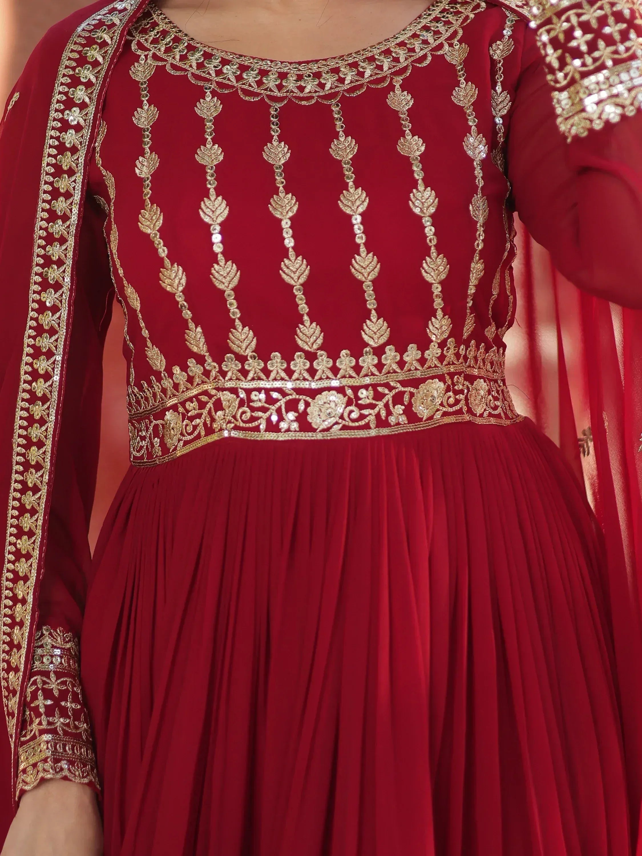 Red ethnic gown with gold embroidery and sequin detailing, perfect for Indian celebrations