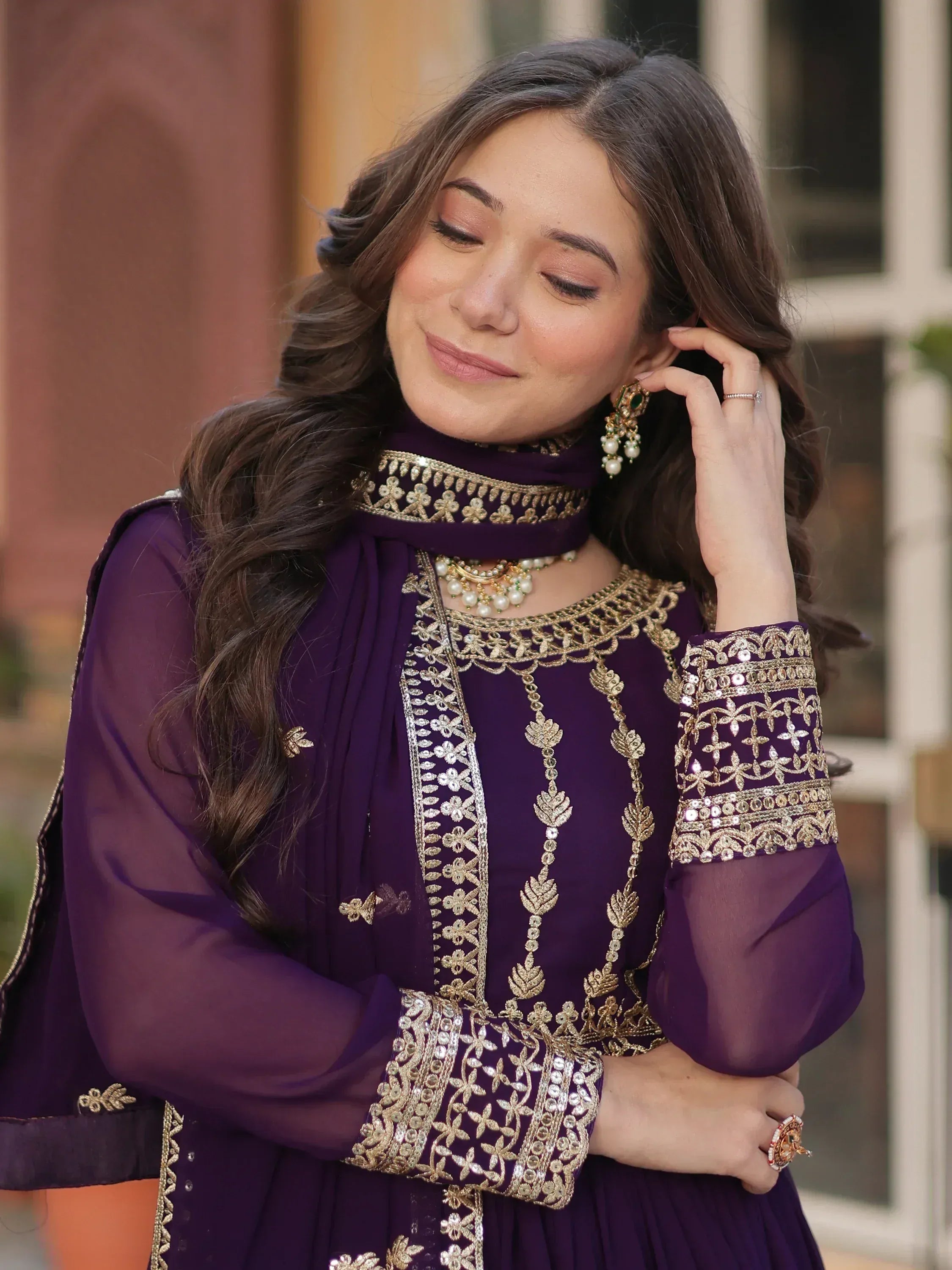 Purple ethnic salwar kameez with gold embroidery and matching dupatta, styled with traditional jewelry.