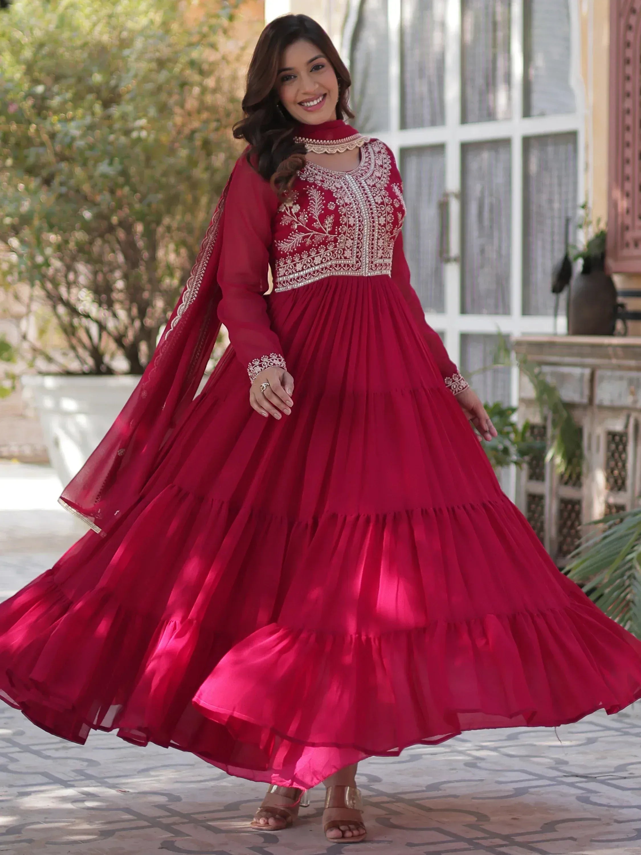 Elegant maroon ethnic gown with intricate embroidery and flared skirt, perfect for festive occasions.