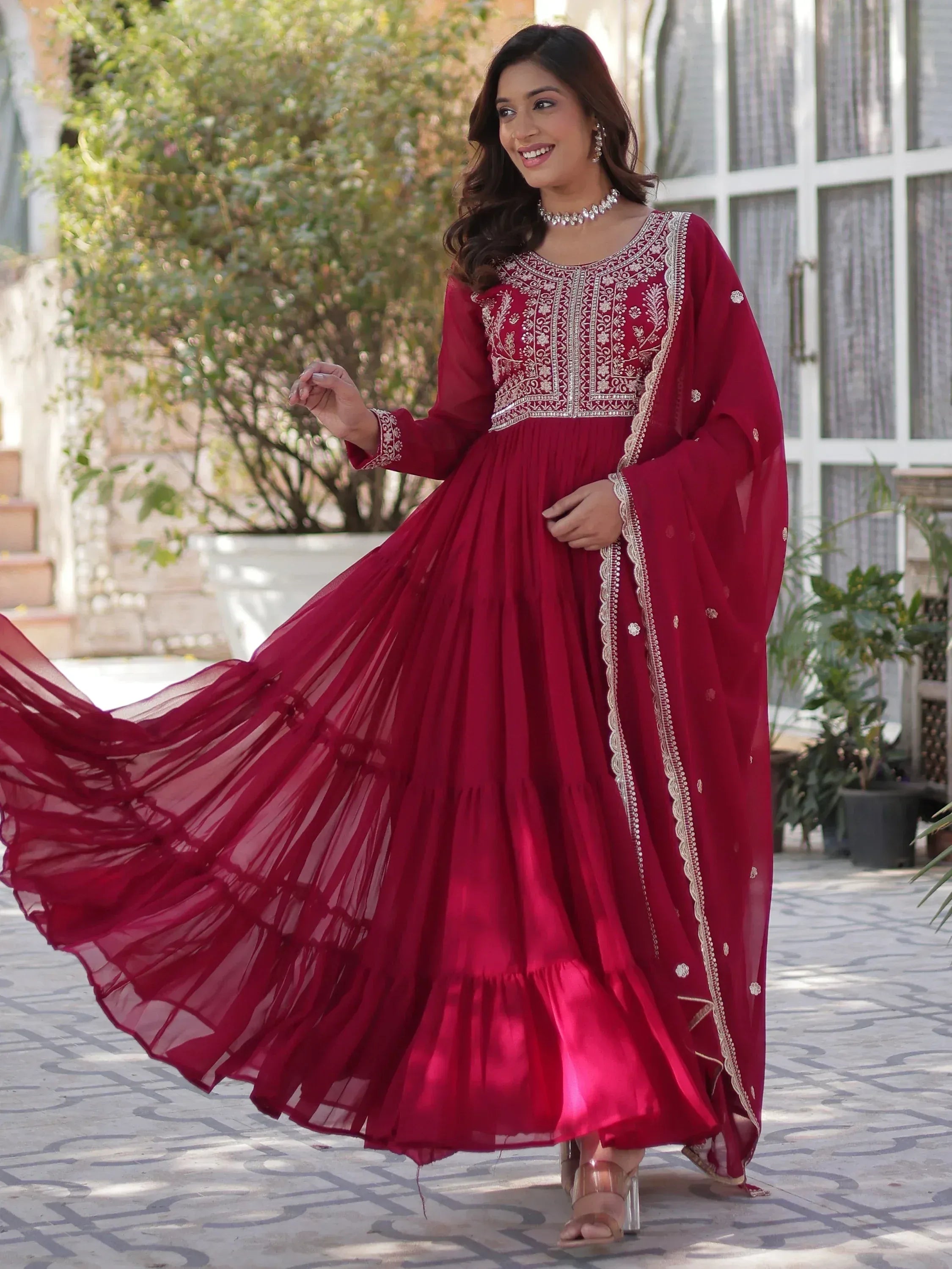 Elegant maroon ethnic gown with intricate embroidery and flowing skirt for festive occasions