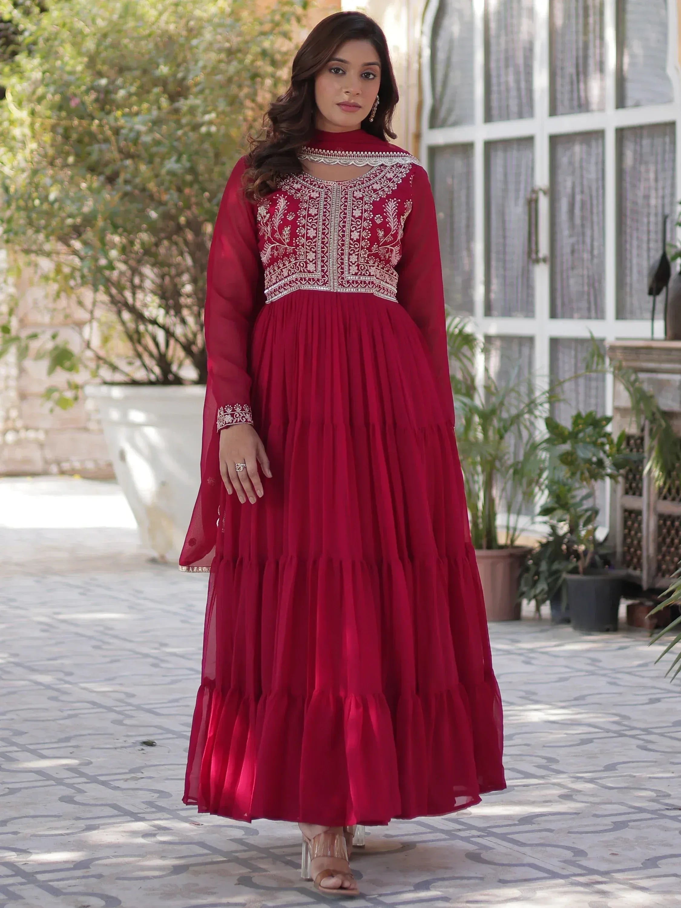 Elegant maroon ethnic gown with intricate embroidery and tiered skirt, perfect for festive occasions.