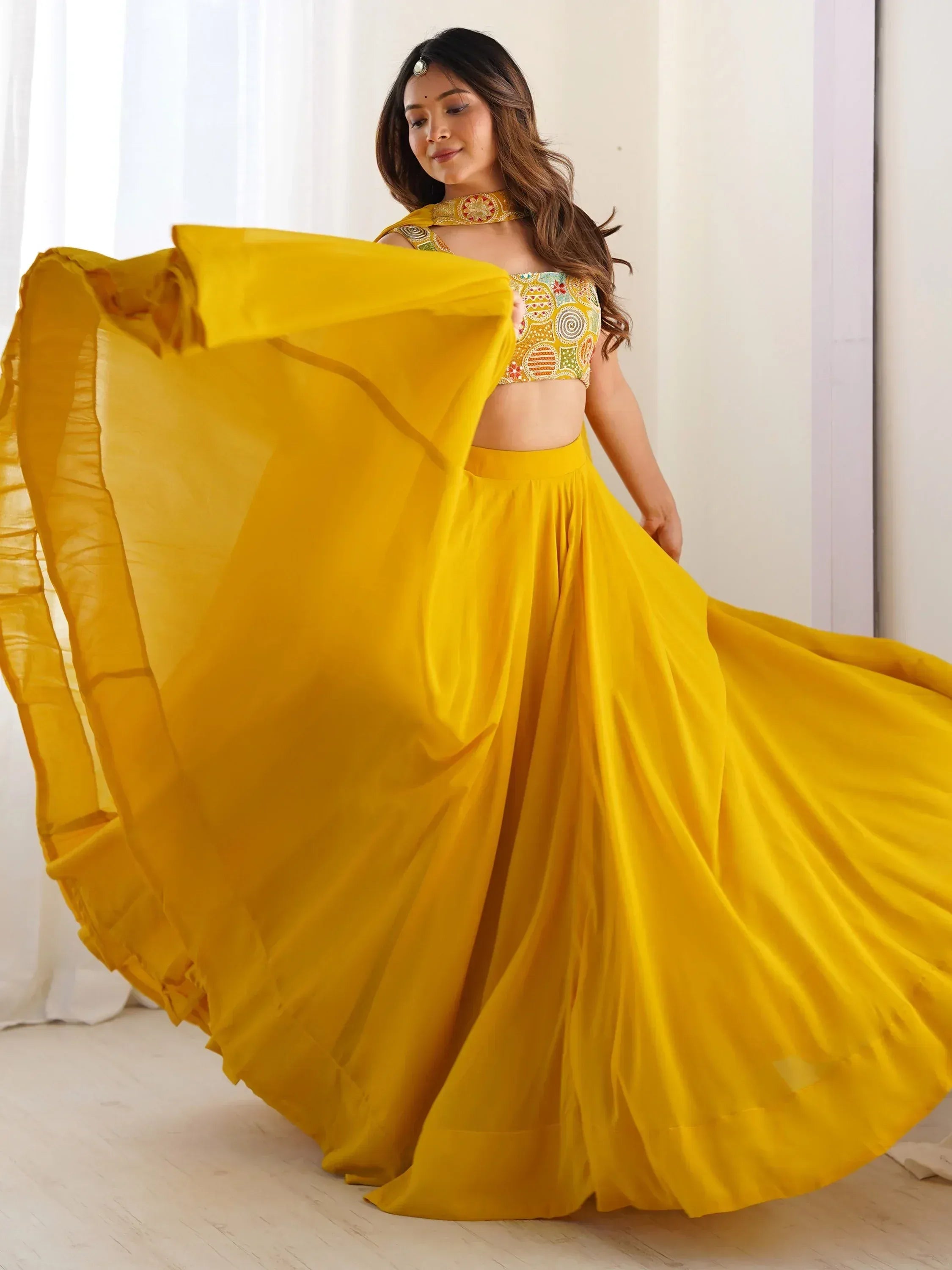 Yellow designer lehenga choli with embroidered blouse and flowing skirt, perfect for Indian ethnic wear occasions.