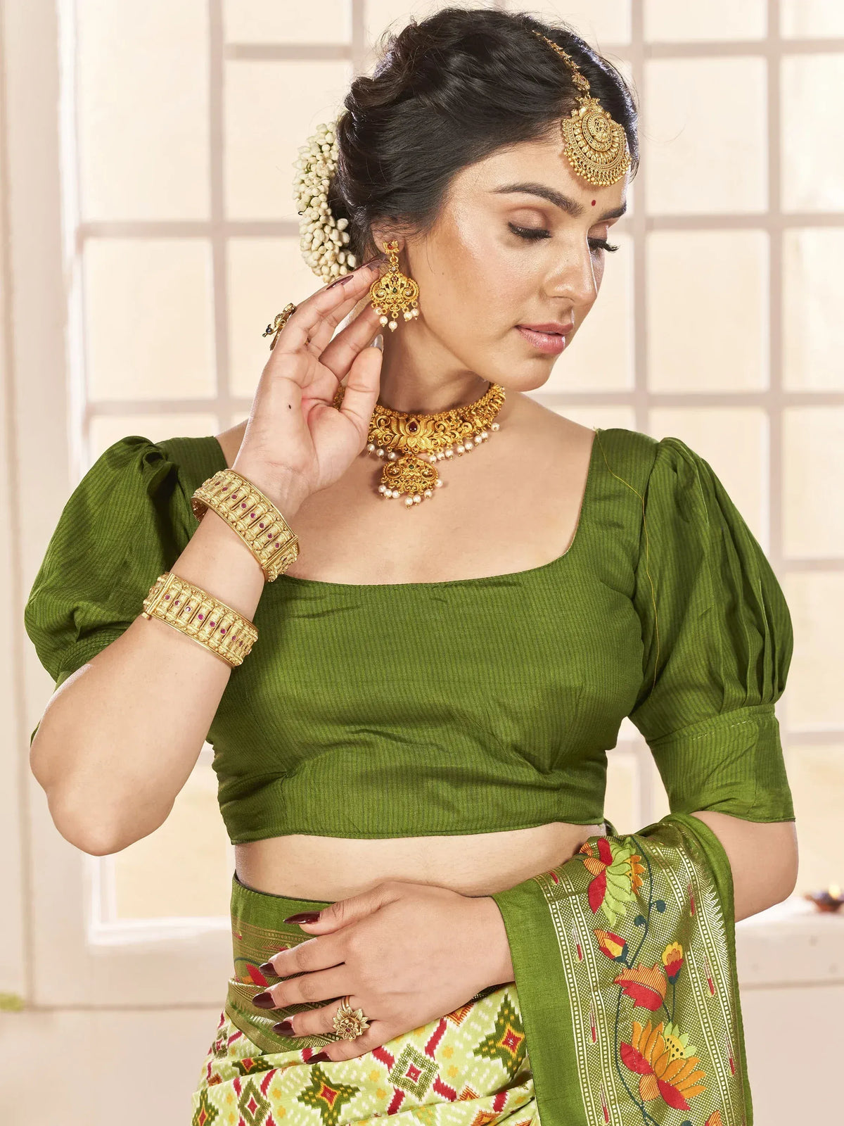 Woman in green ethnic saree with gold jewelry, floral print, and traditional Indian blouse