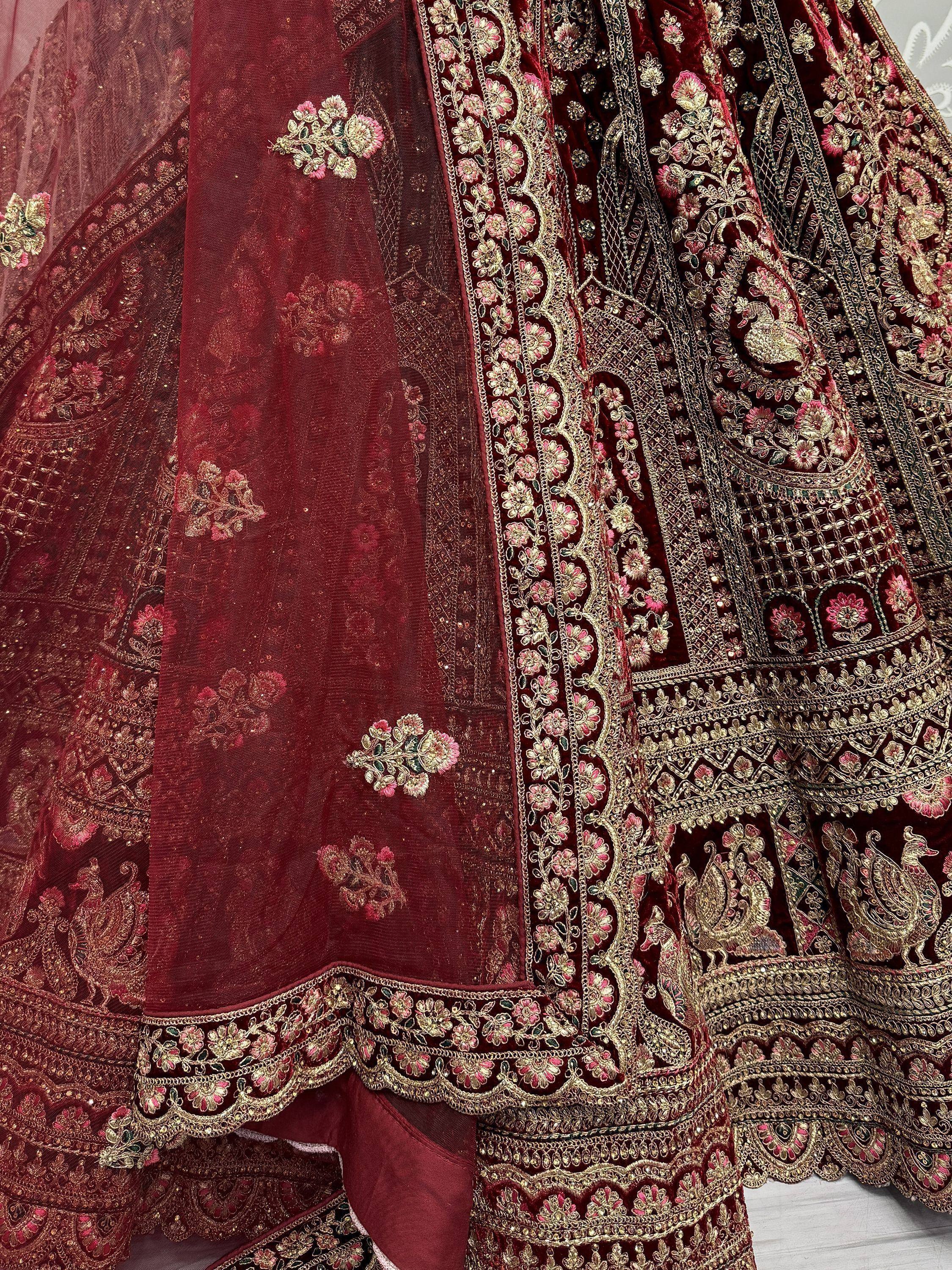 Luxury maroon velvet lehenga with gold floral embroidery and peacock motifs, perfect for Indian weddings.