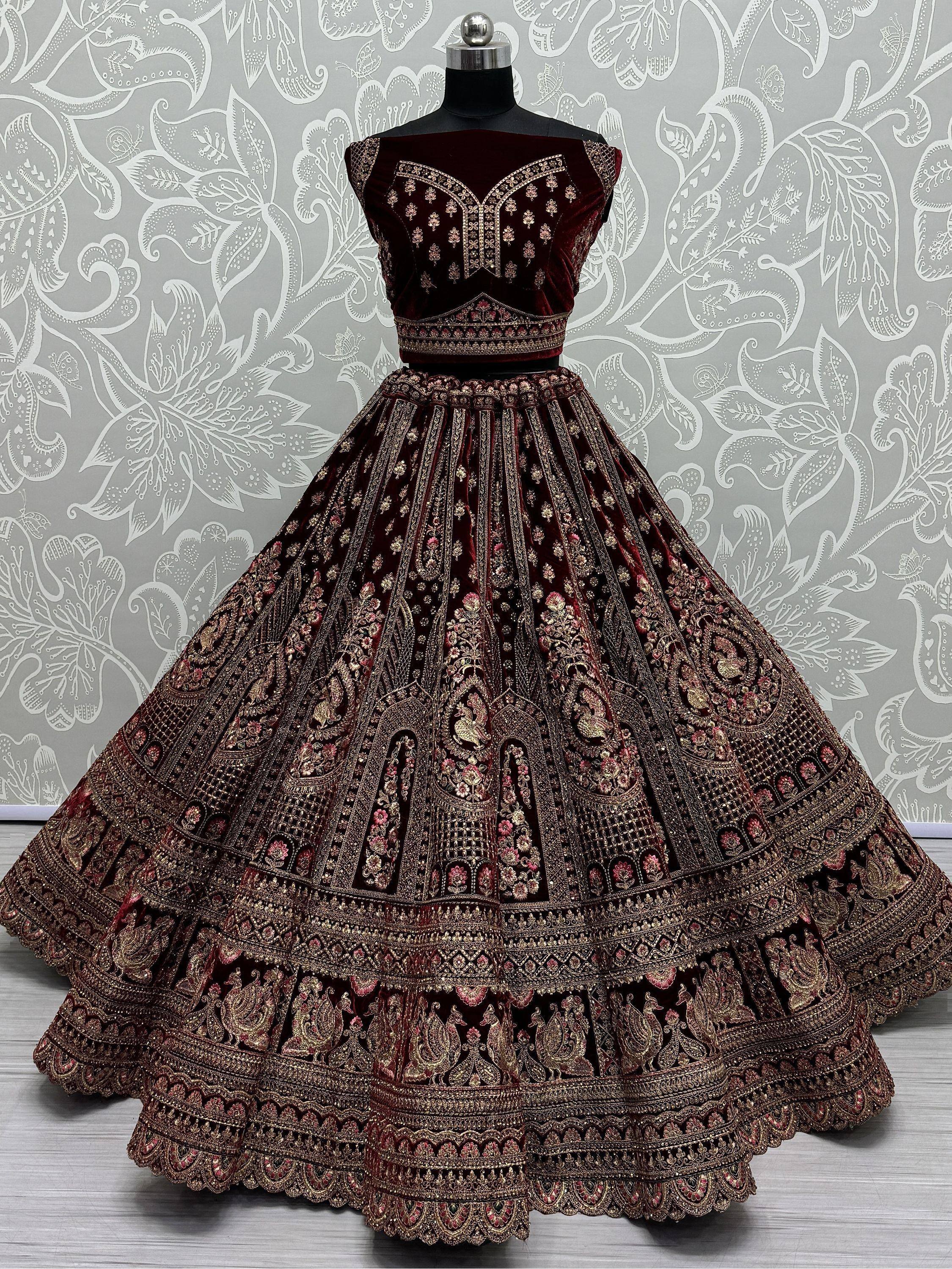 Luxury maroon velvet lehenga choli with heavy gold embroidery, perfect for Indian weddings and festive occasions.