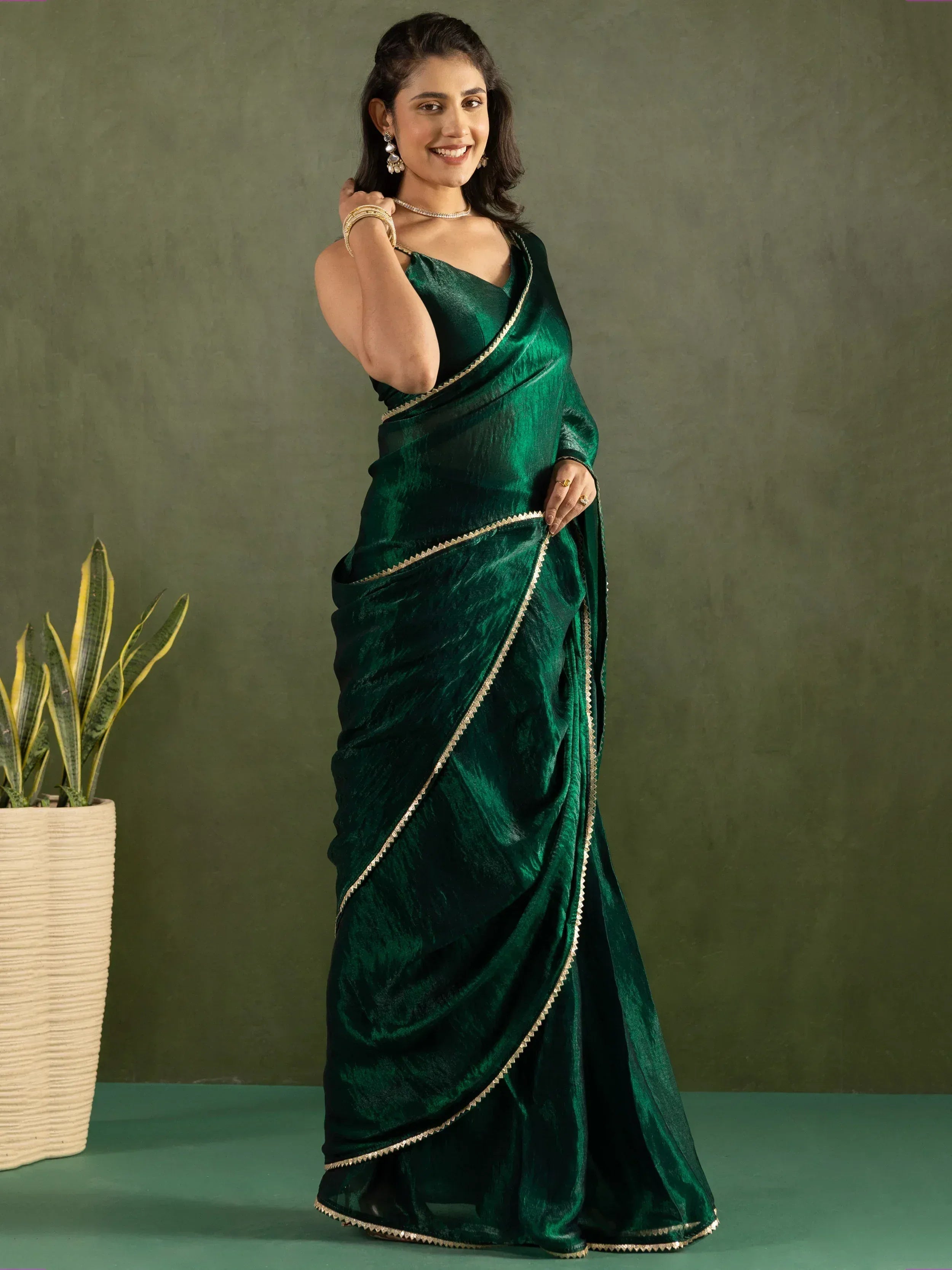 Emerald green velvet saree with gold trim, styled with ethnic jewelry for Indian occasions