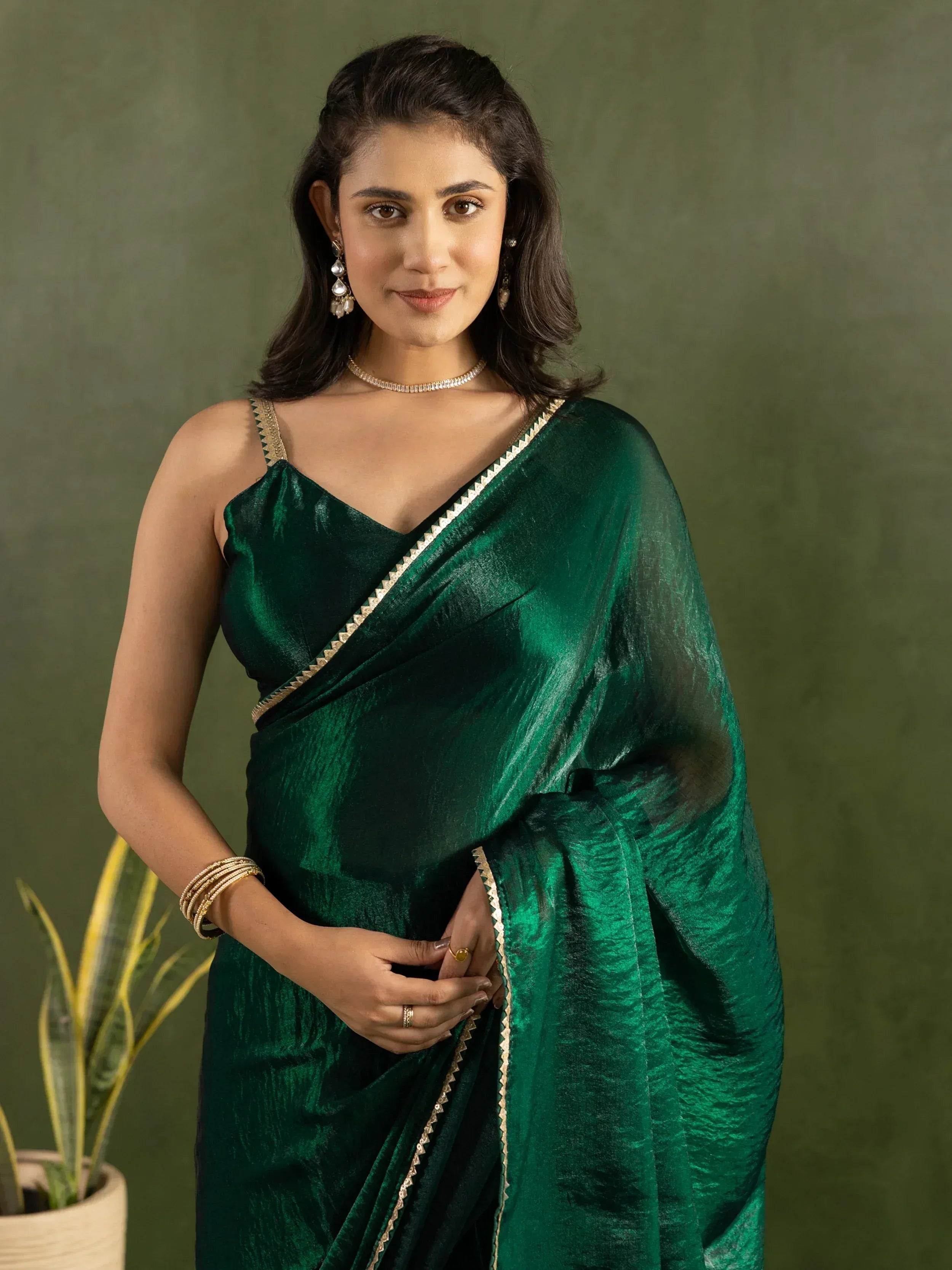 Emerald green velvet saree with gold trim, styled with ethnic jewelry for festive occasions