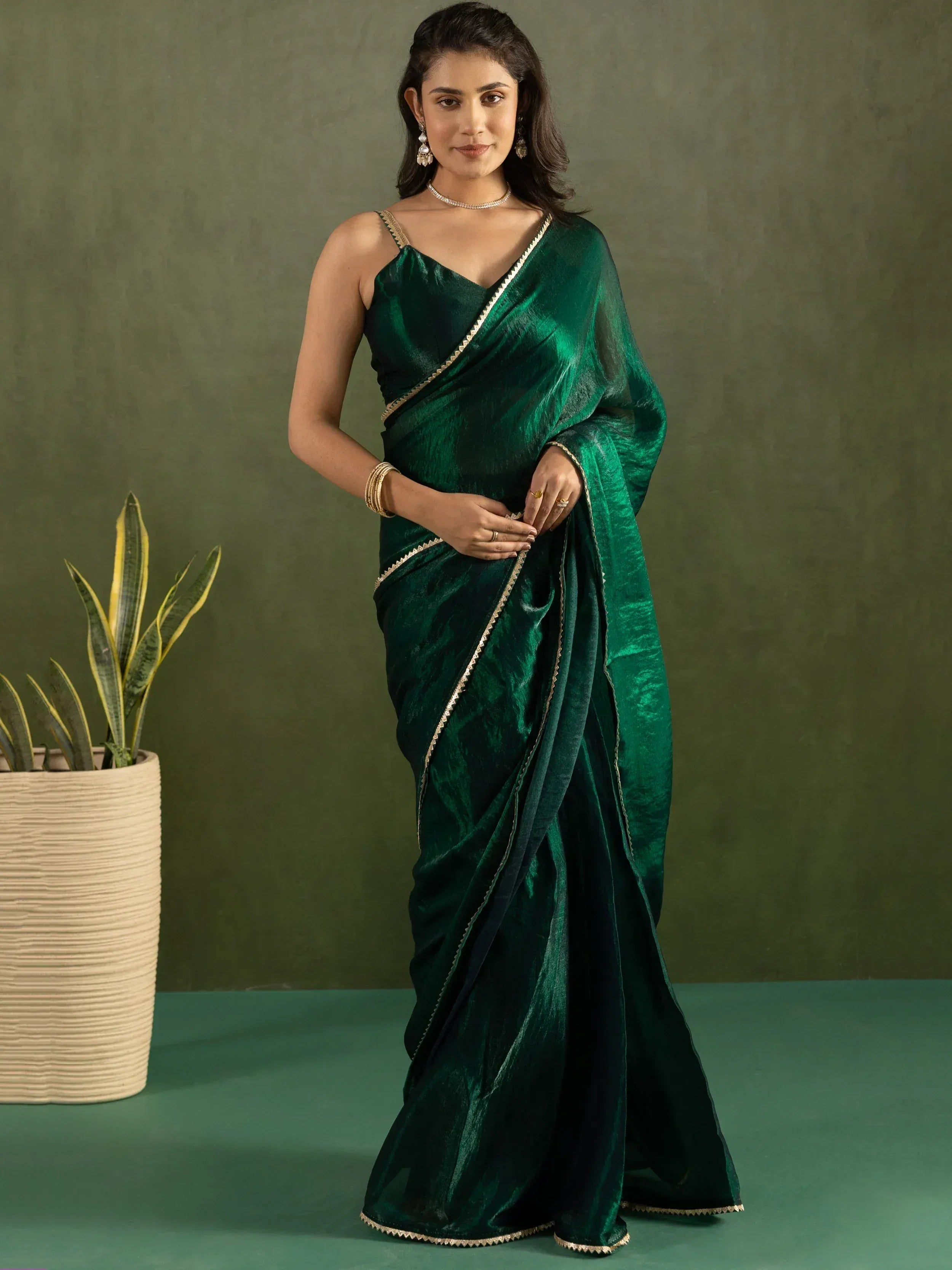 Emerald green velvet saree with gold trim, styled with ethnic jewelry for festive occasions.
