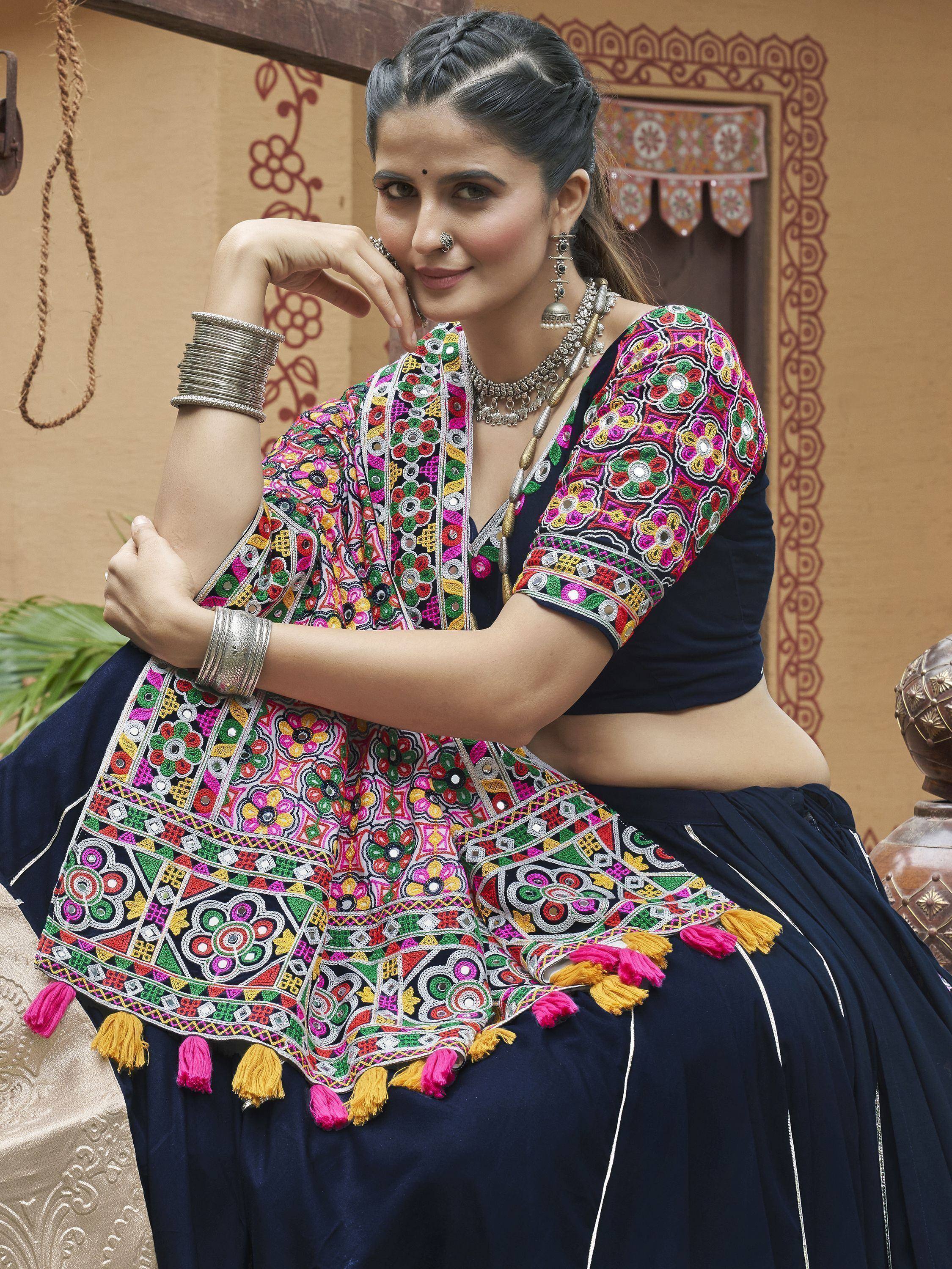 Woman in vibrant embroidered Indian ethnic wear with mirror work and tassels, styled with traditional jewelry