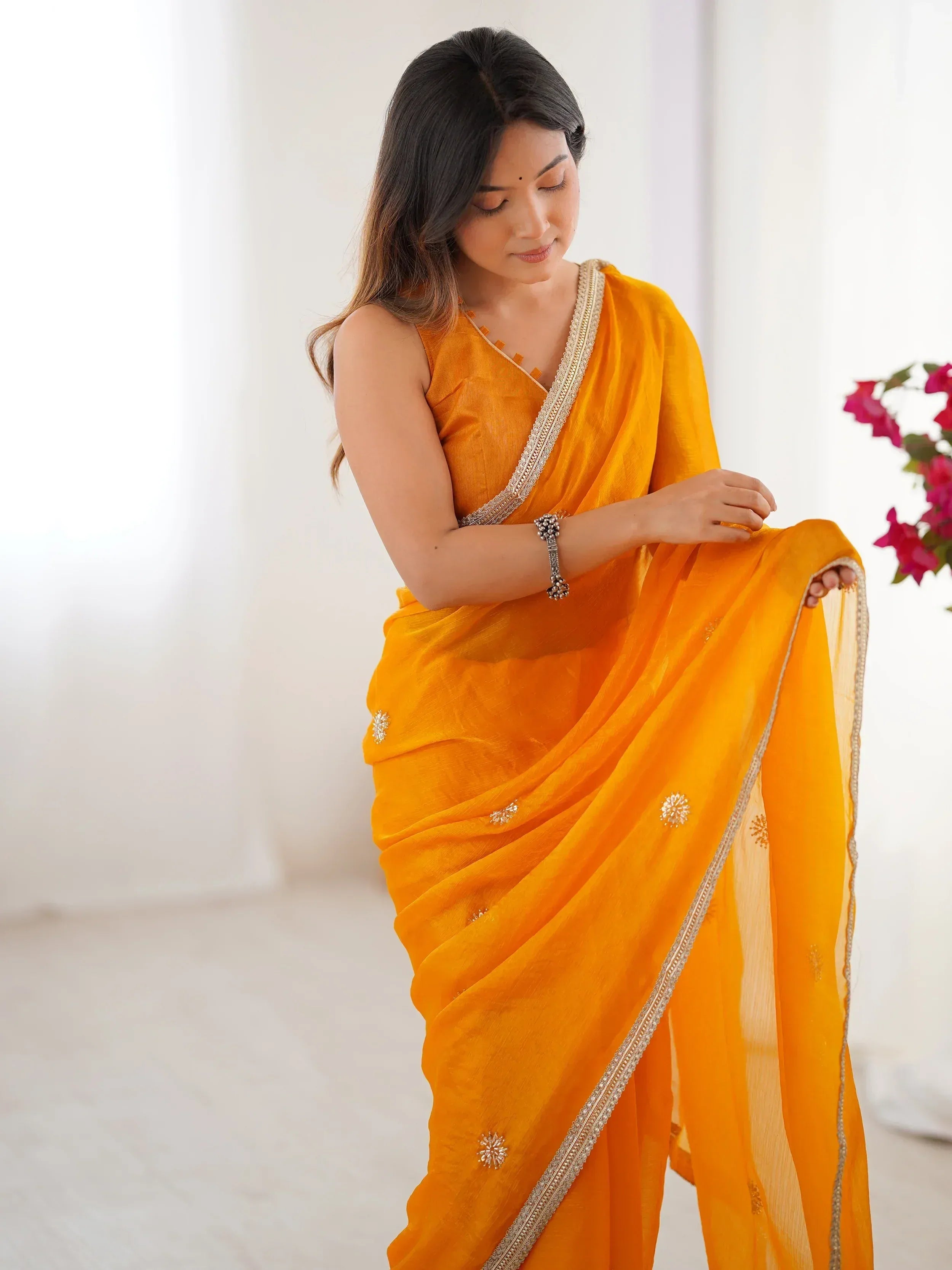 Woman in vibrant orange saree with gold embroidery, perfect for Indian ethnic wear occasions