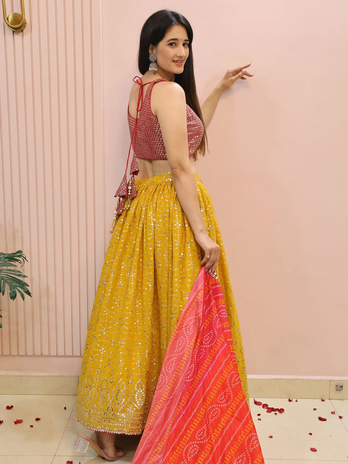 Woman in vibrant yellow lehenga with red sequin blouse and dupatta, perfect for Indian ethnic occasions