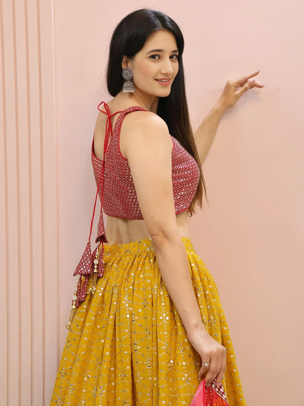 Woman in red sequin blouse and yellow lehenga with tassels, ethnic Indian wear