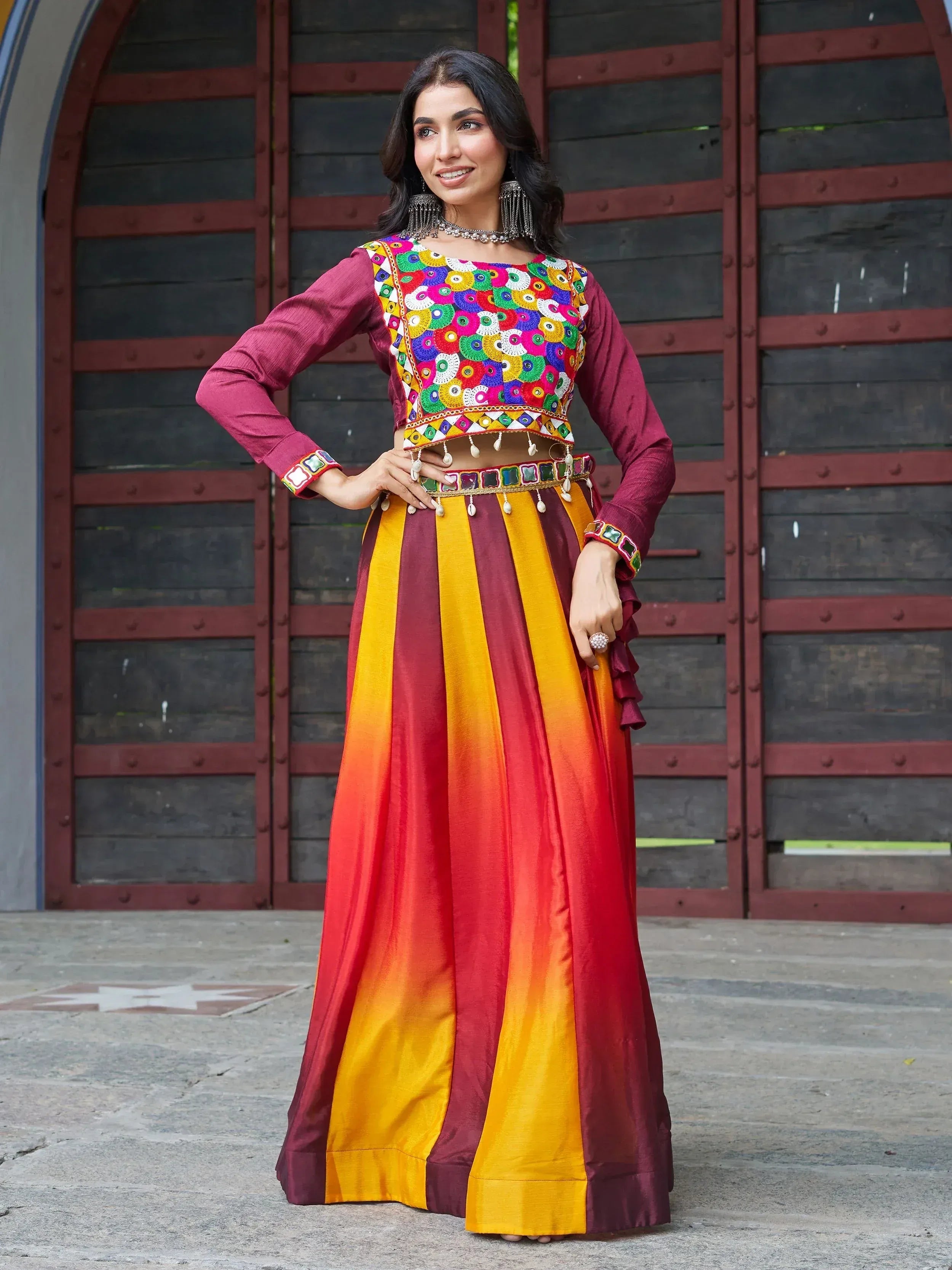 Woman in colorful embroidered Indian lehenga choli with mirror work, maroon and yellow ombre skirt, traditional ethnic wear
