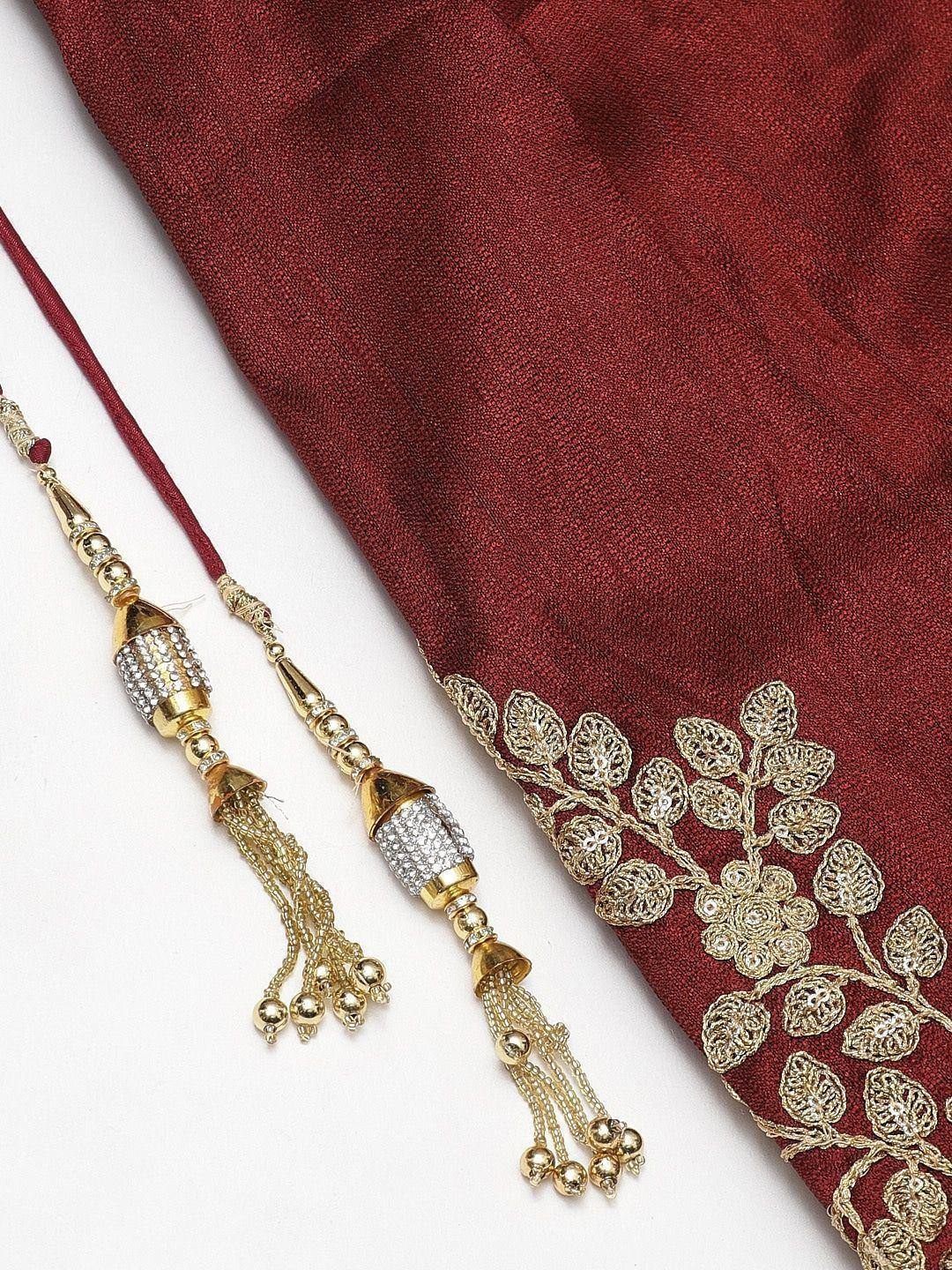 Maroon ethnic saree with gold floral embroidery and matching tassel jewelry