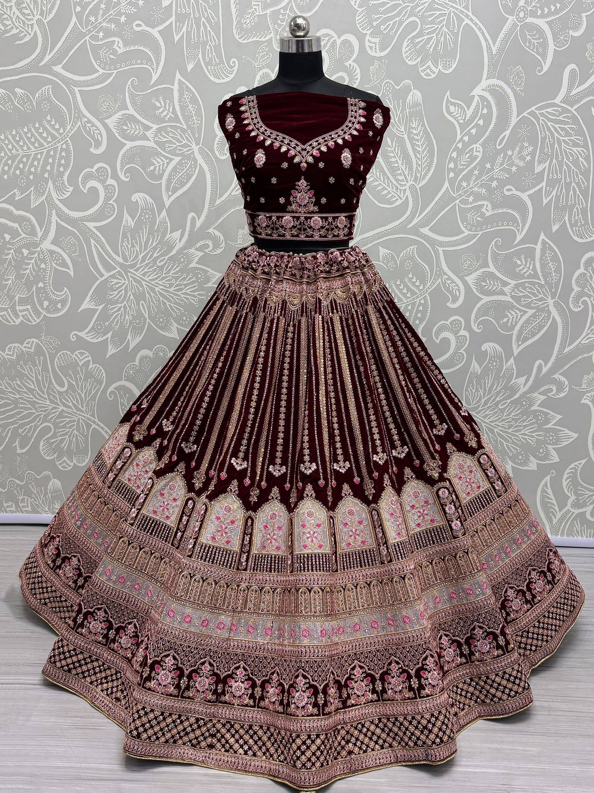 Maroon velvet designer lehenga choli with heavy gold and pink embroidery, perfect for weddings and festive occasions.