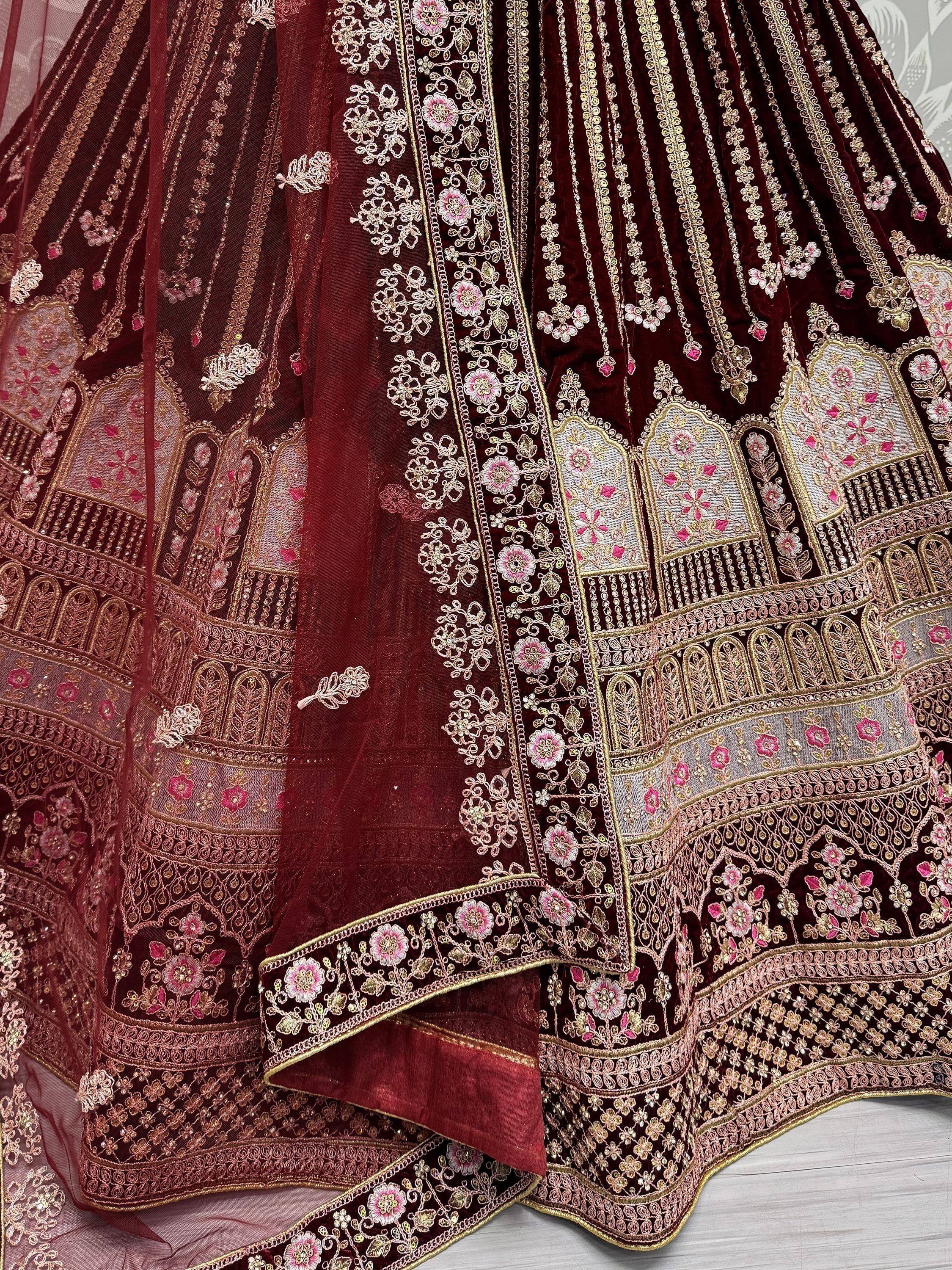 Maroon velvet lehenga choli with intricate gold and pink floral embroidery, perfect for Indian weddings.