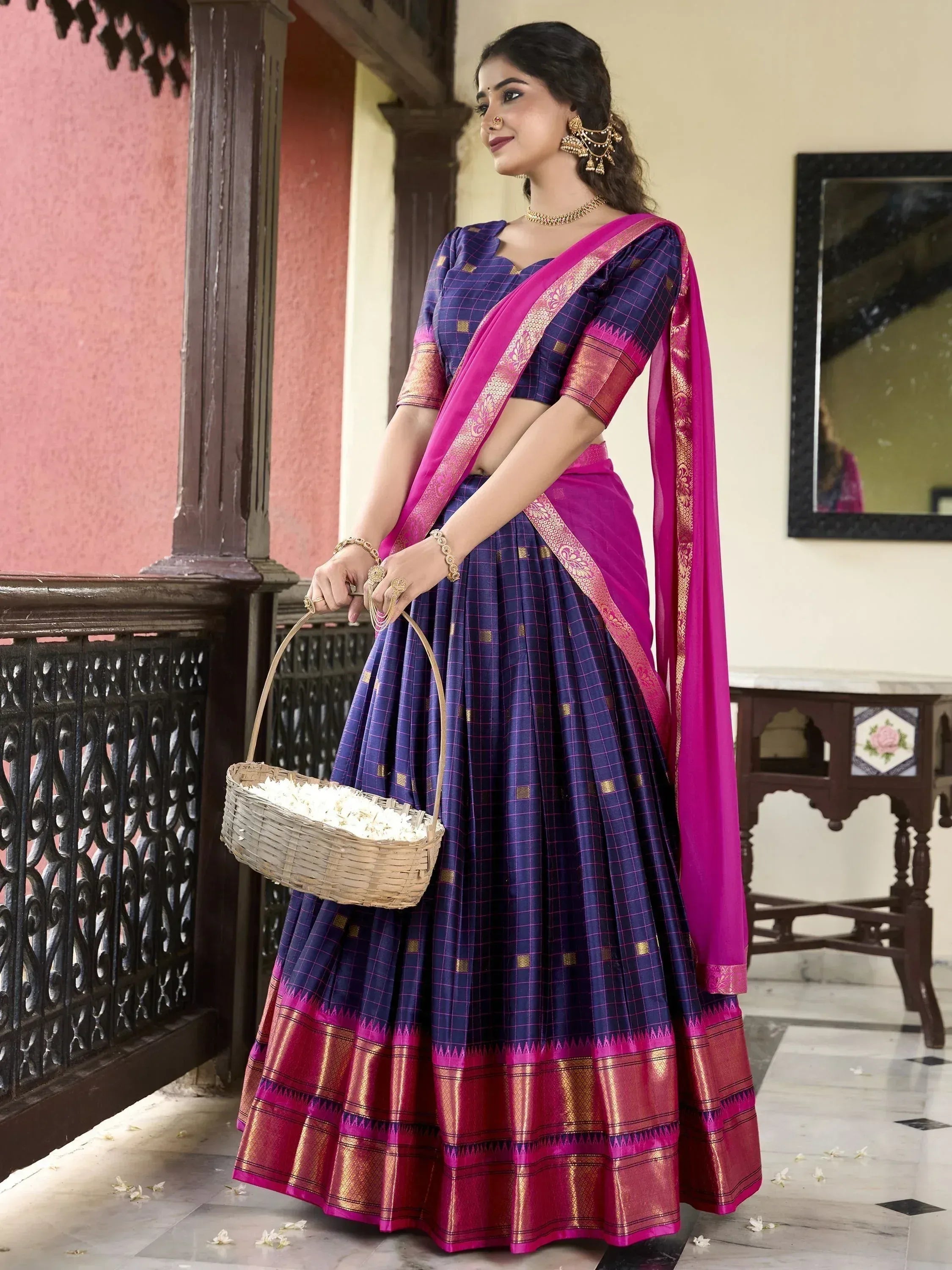 Woman in purple and pink checkered lehenga choli with golden border, holding flower basket