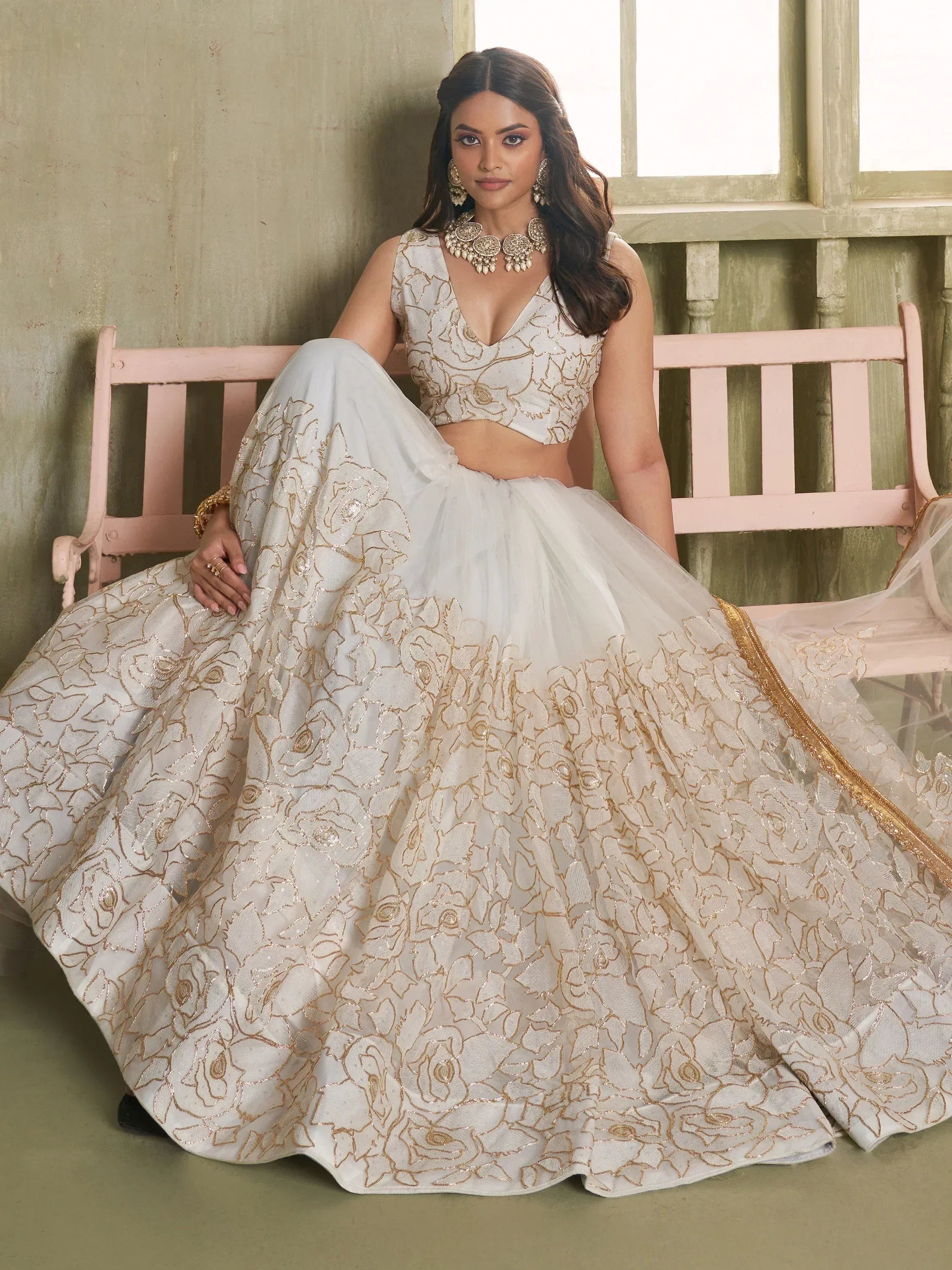 Elegant white lehenga choli with gold floral embroidery, perfect for Indian weddings and festive occasions.