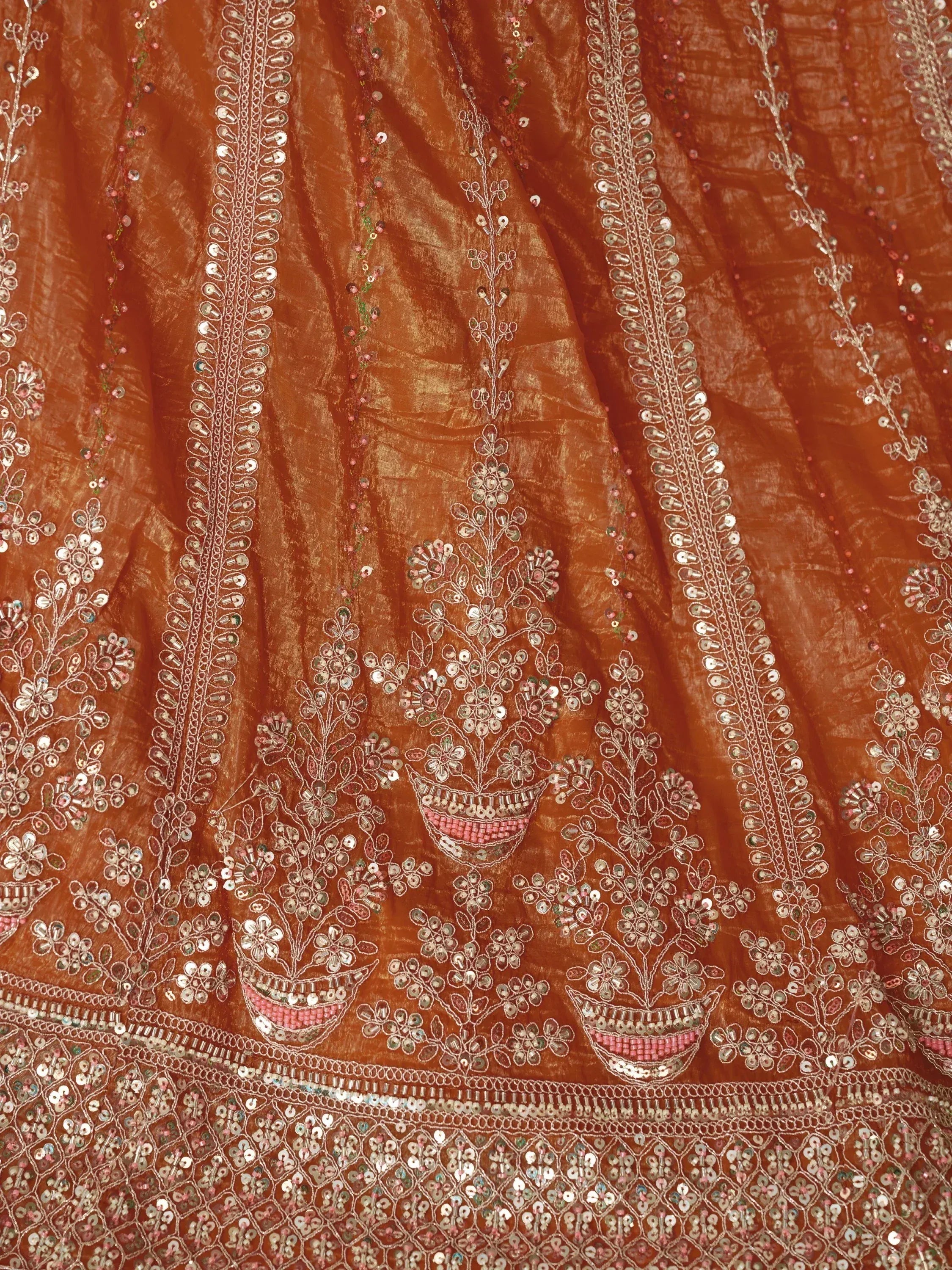 Rust orange ethnic wear with intricate mirror and sequin embroidery, floral motifs, and detailed border work.
