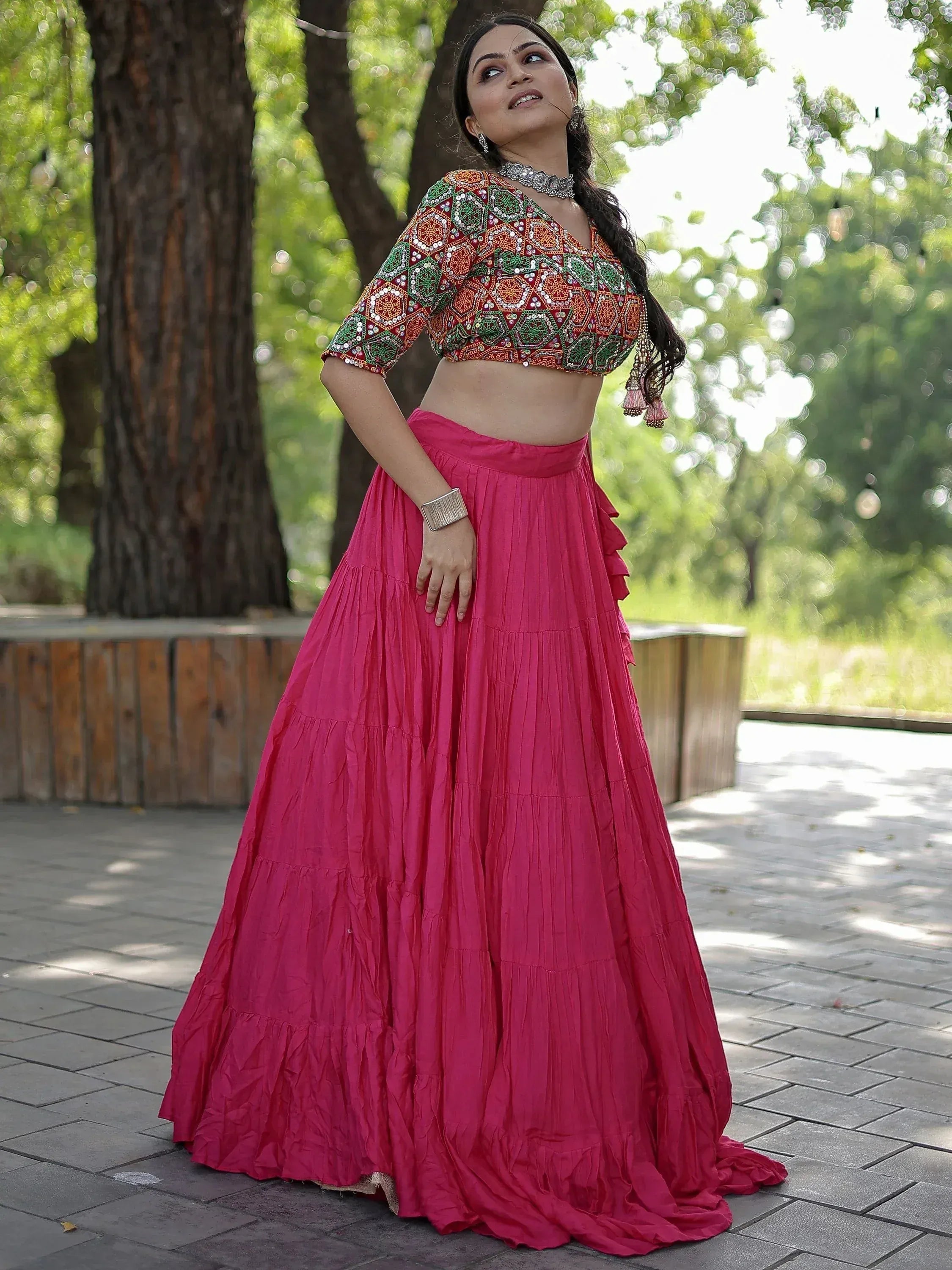 Woman in vibrant pink lehenga with embroidered red and green crop top, styled for Indian ethnic wear