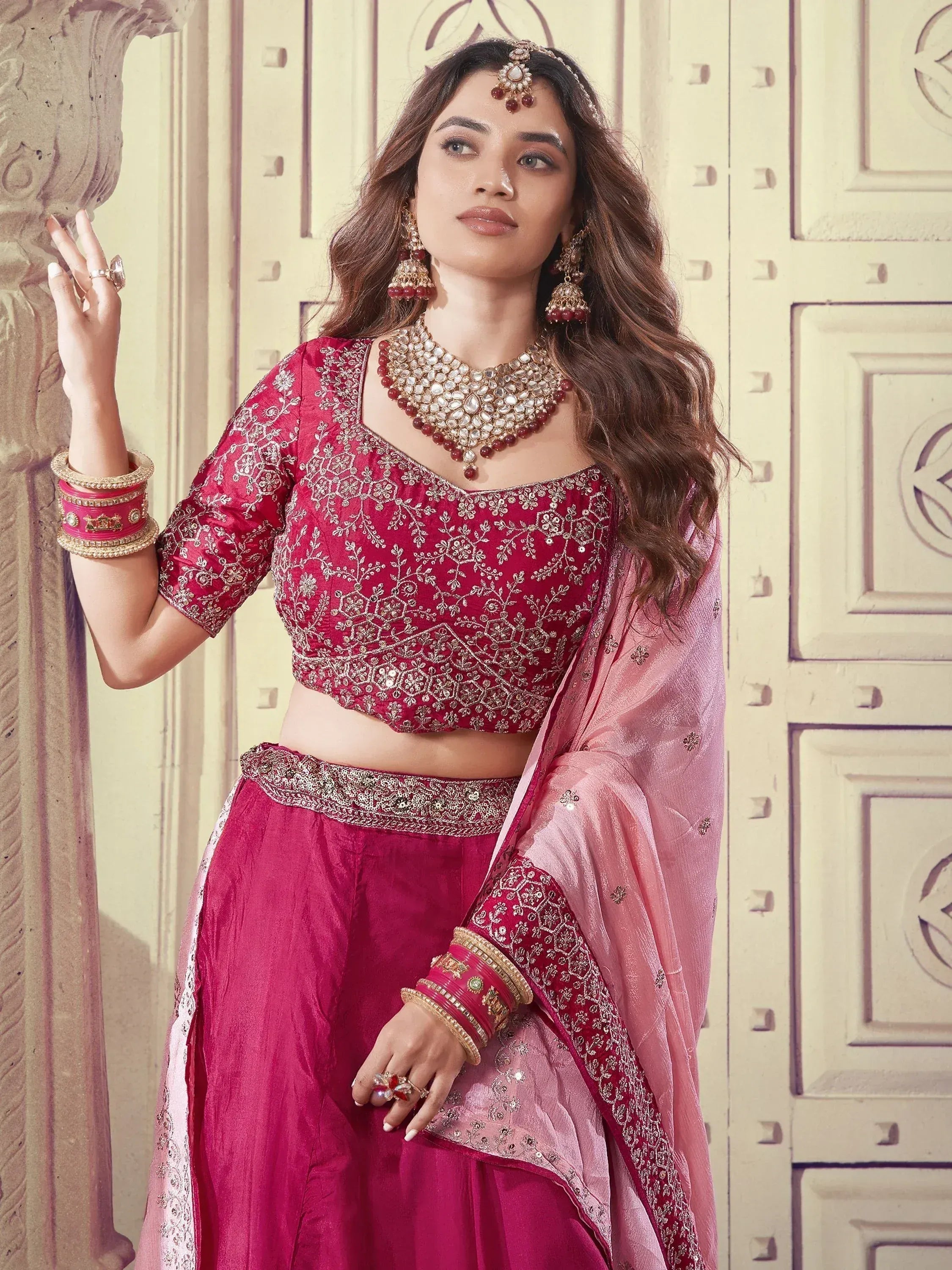 Elegant maroon lehenga choli with gold embroidery, pink dupatta, and traditional jewelry for Indian ethnic wear