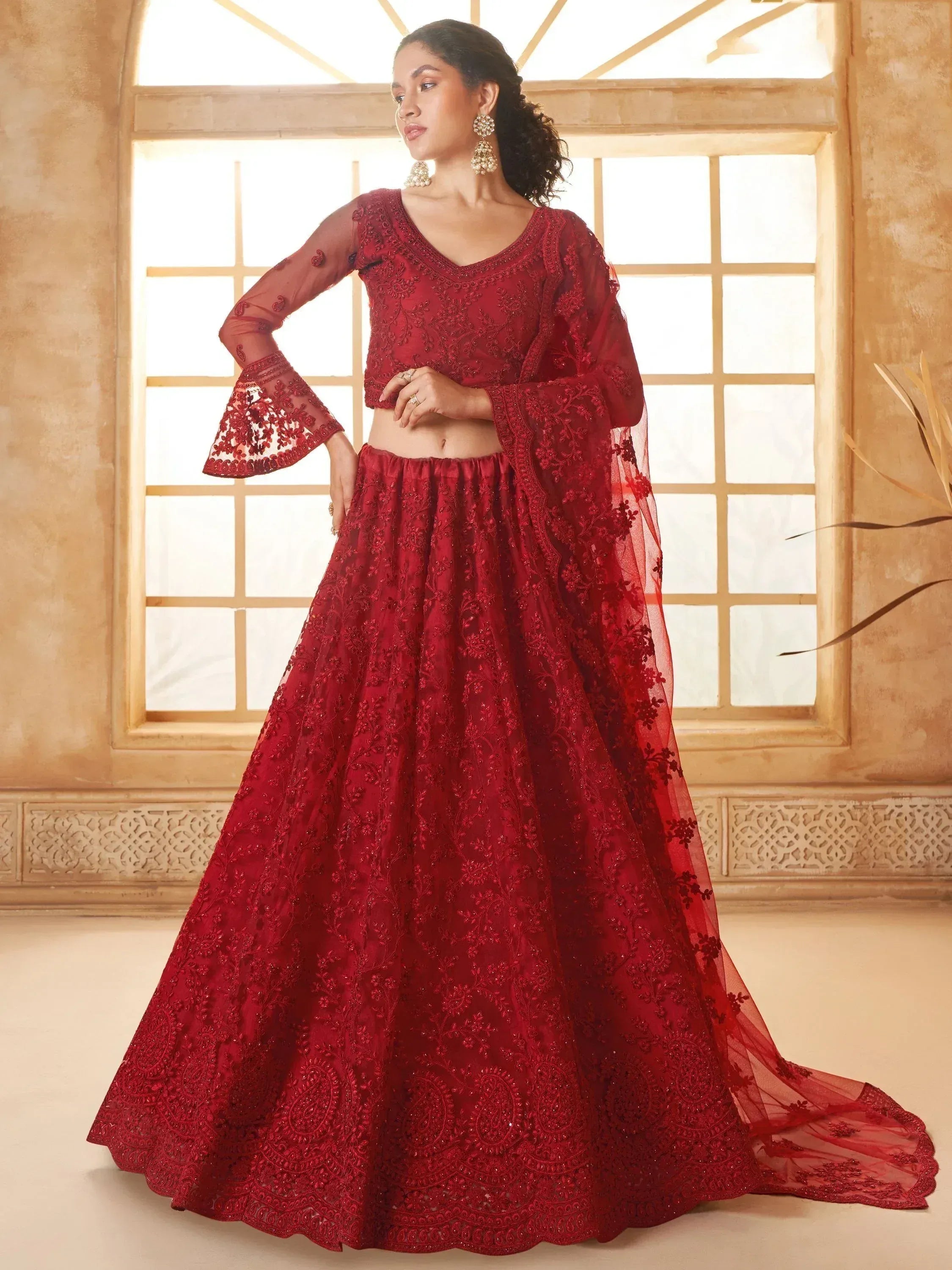 Red embroidered lehenga choli with bell sleeves, perfect for Indian weddings and festive occasions