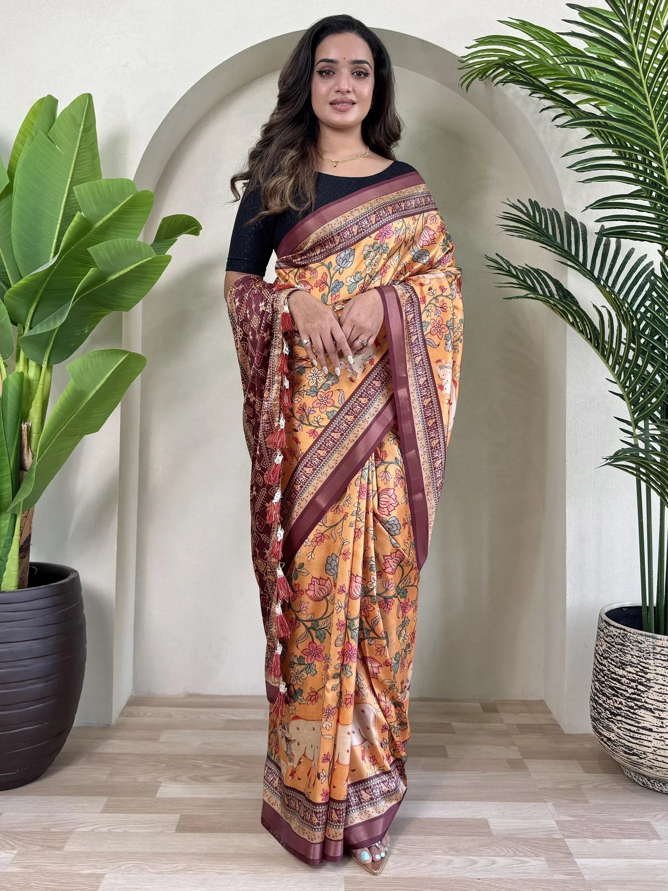 Woman in floral print saree with maroon border, ethnic Indian wear, styled with black blouse and tassels