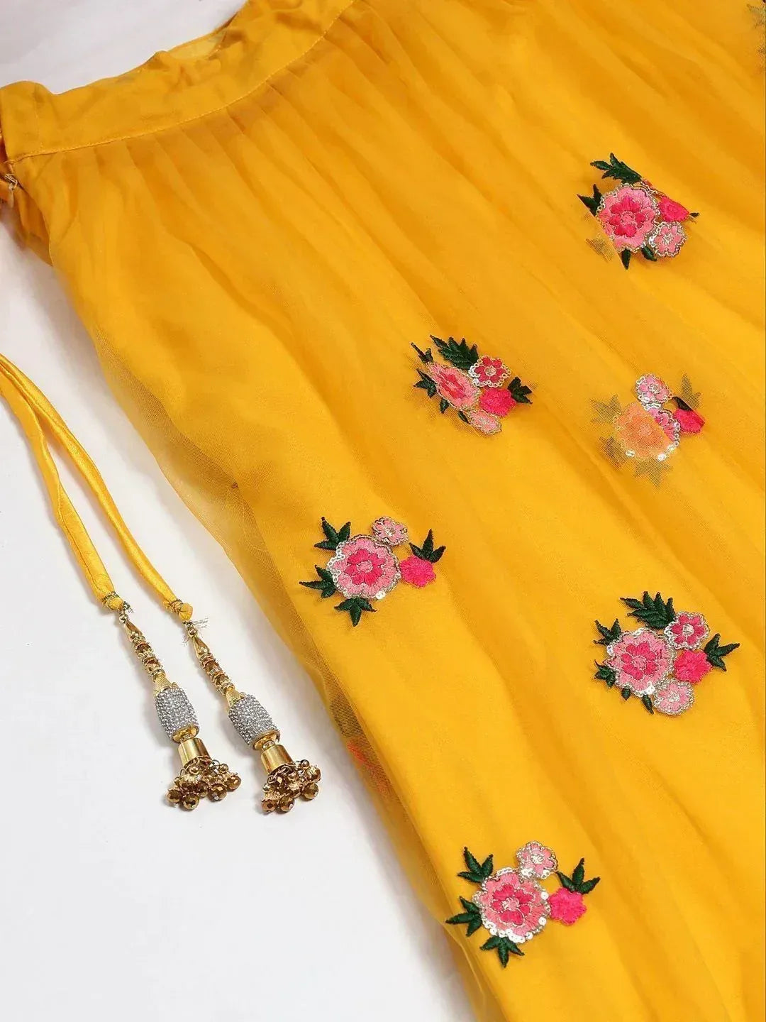 Yellow ethnic gown with pink floral embroidery and gold tassels, perfect for Indian festive wear