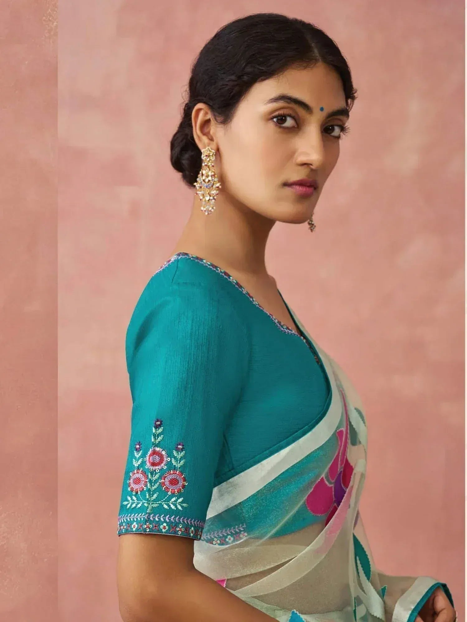 Teal embroidered saree blouse with floral detailing, paired with printed saree, perfect for Indian ethnic wear.