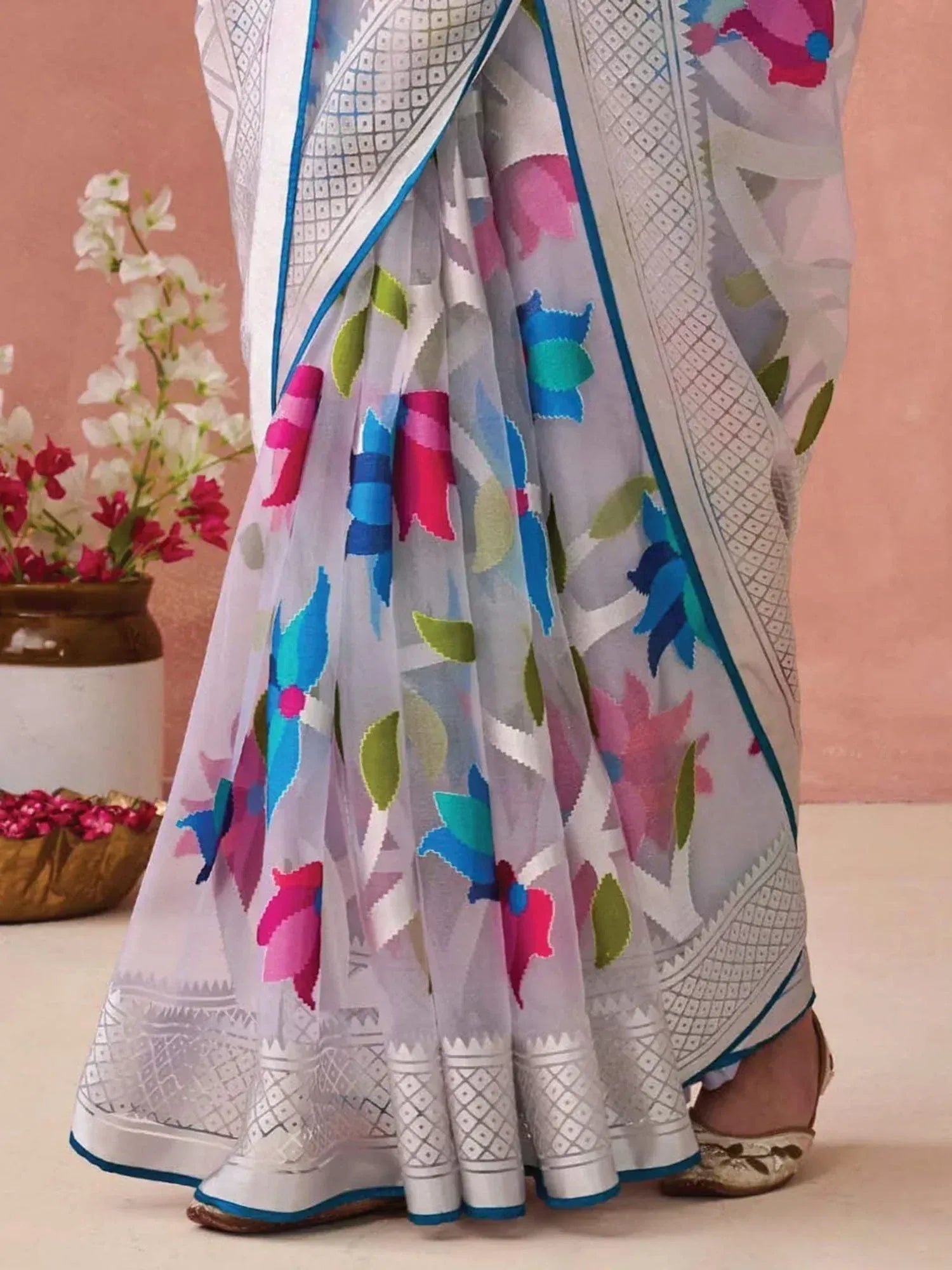 White saree with colorful floral print and geometric border, styled with ethnic footwear