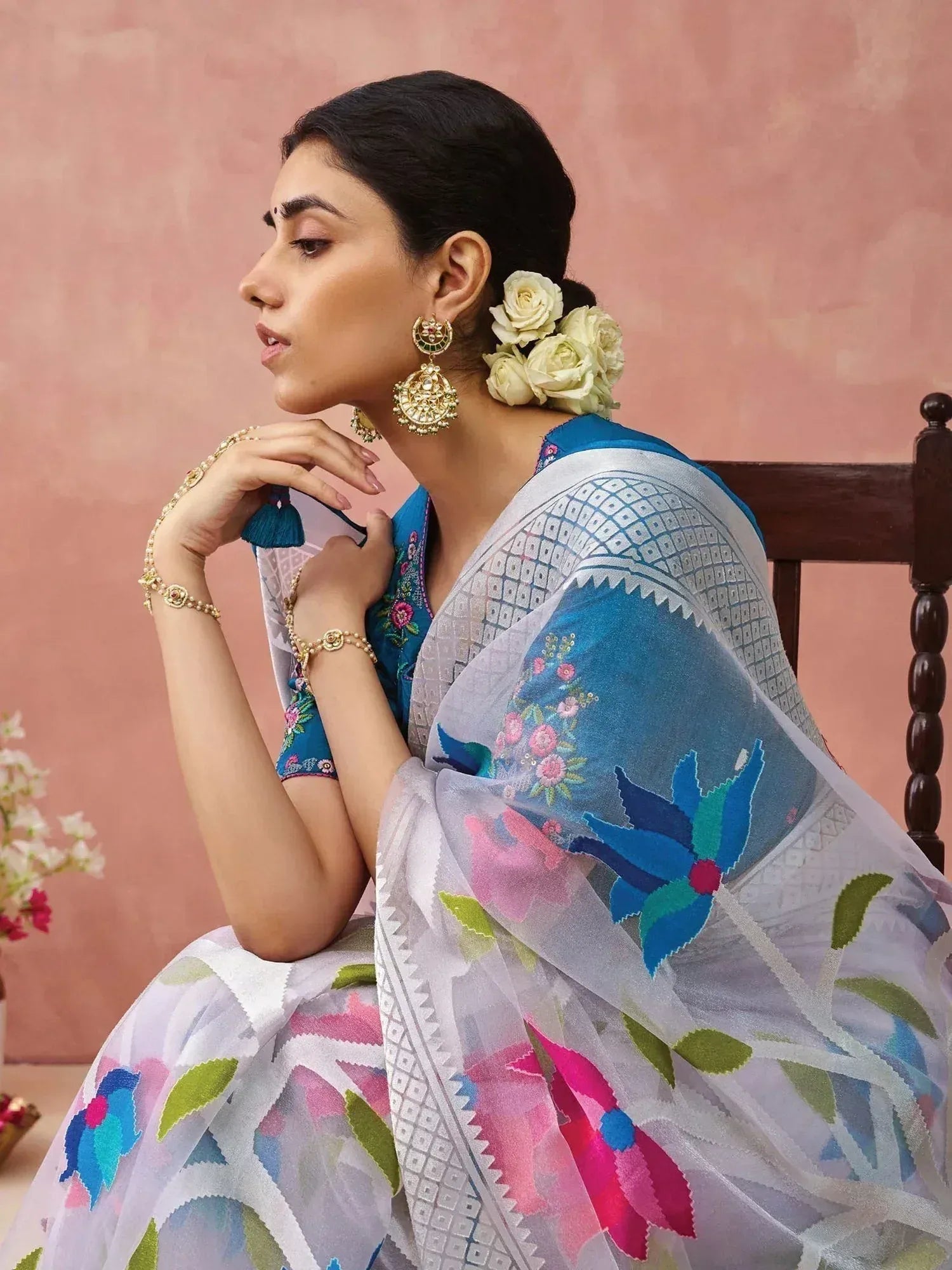 Woman in blue floral embroidered saree with gold jewelry, styled for Indian ethnic wear