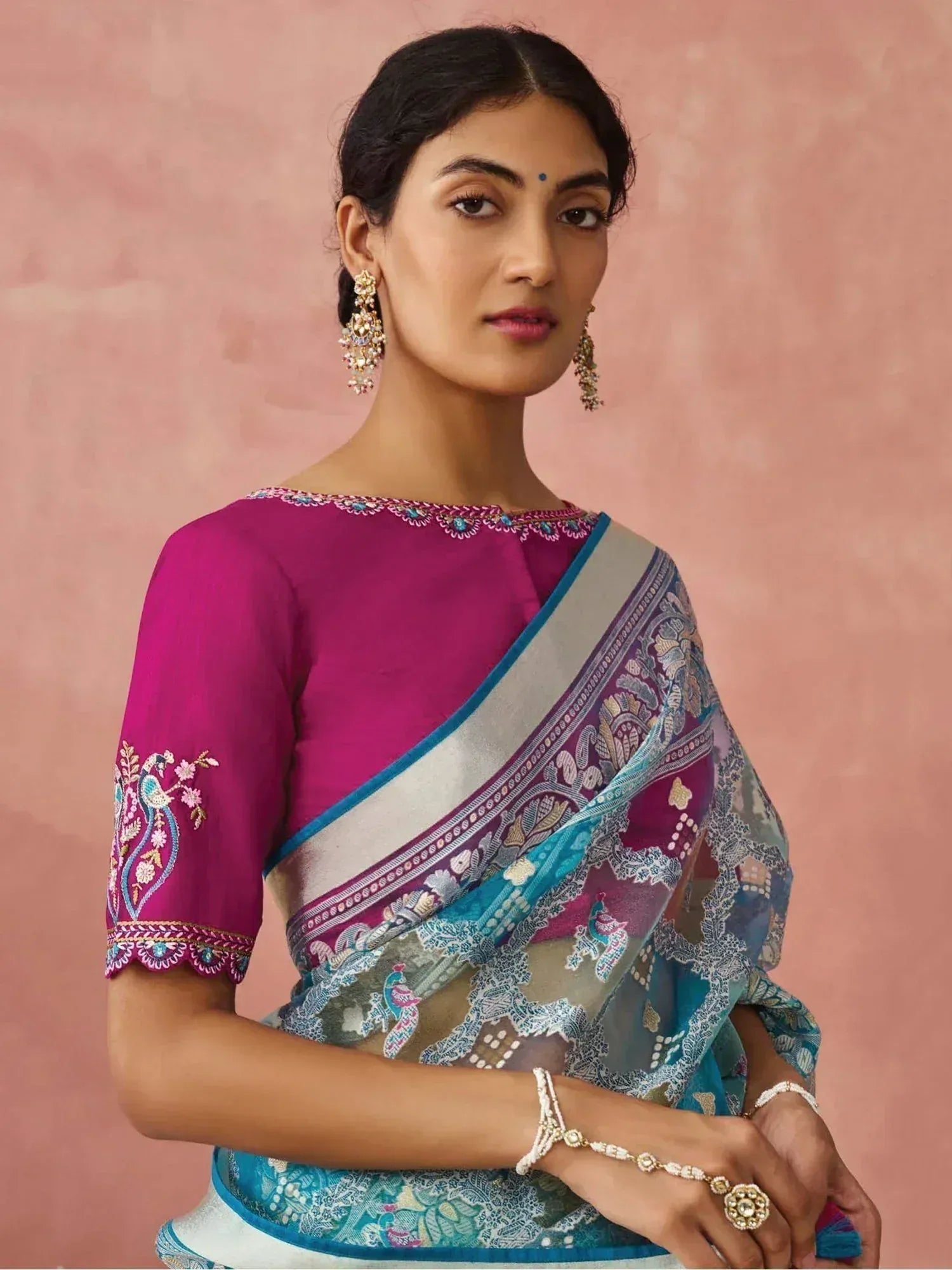 Woman in vibrant pink embroidered blouse with peacock print saree, perfect for Indian ethnic occasions
