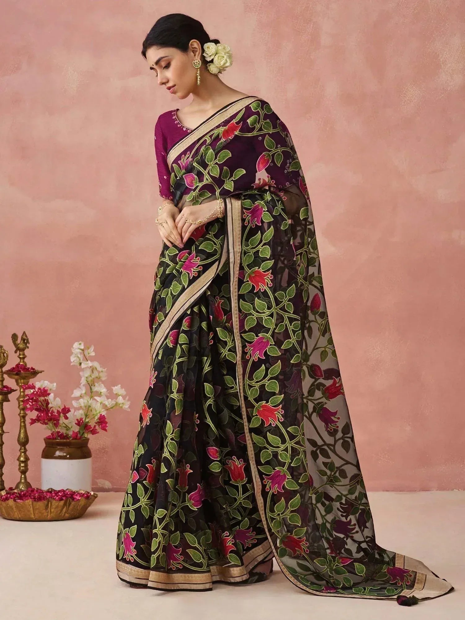 Elegant black saree with floral print and gold border, paired with purple blouse for Indian ethnic wear