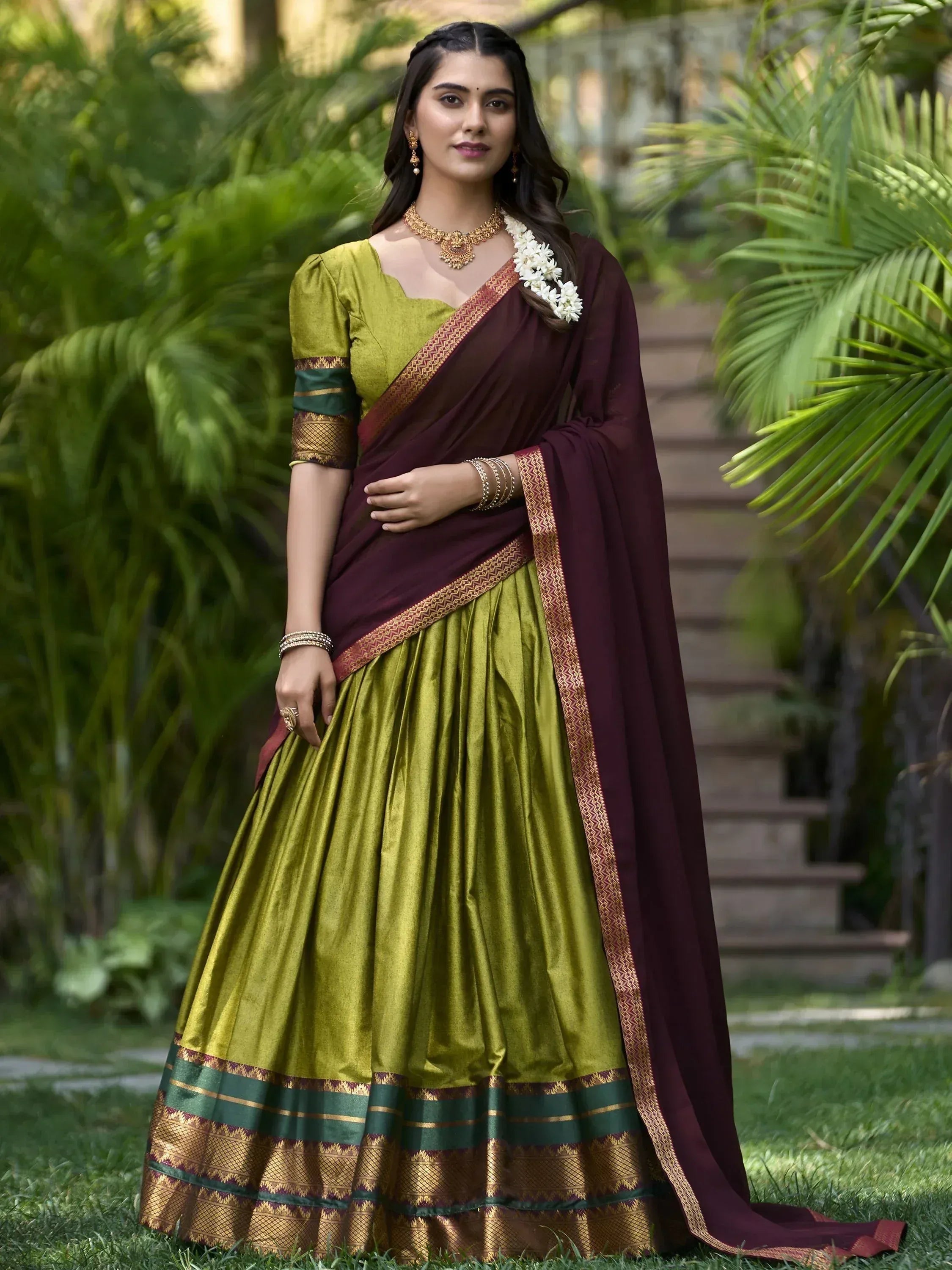 Woman in olive green and maroon designer lehenga choli with gold border, perfect for Indian ethnic occasions