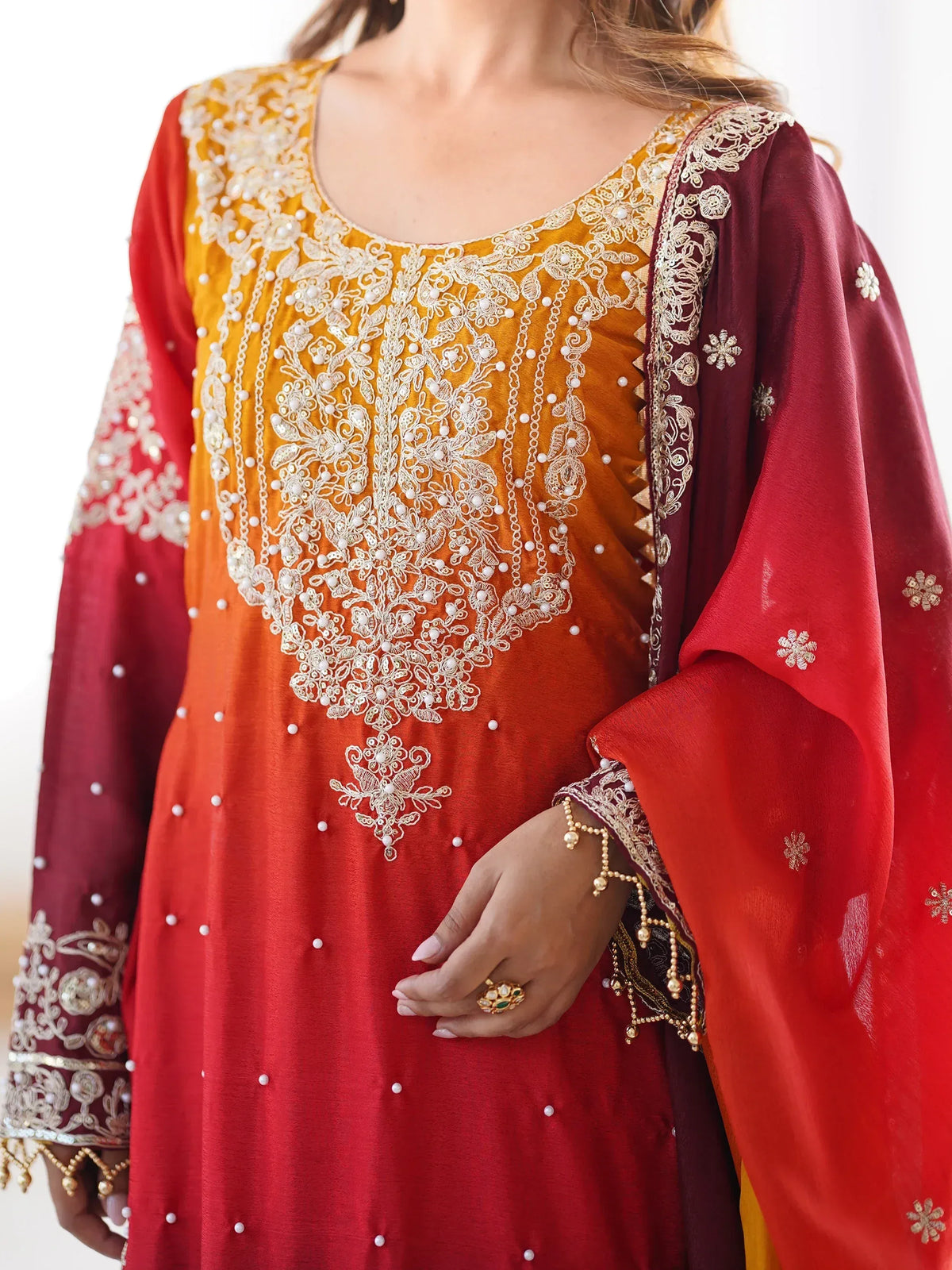 Elegant red and mustard Indian salwar kameez with intricate white embroidery and pearl detailing, perfect for festive occasions.