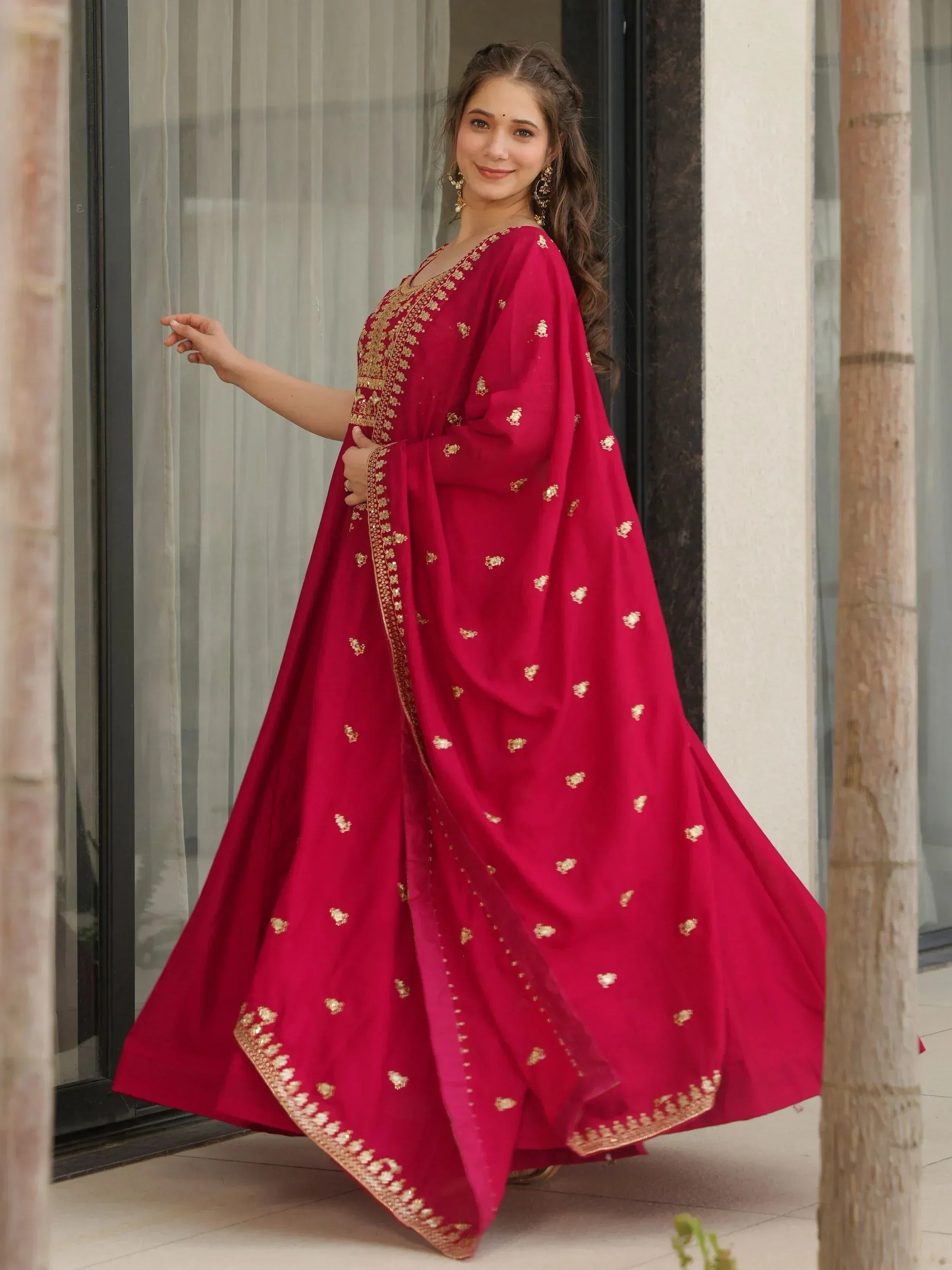Woman in red ethnic gown with gold embroidery, perfect for Indian weddings and festive occasions