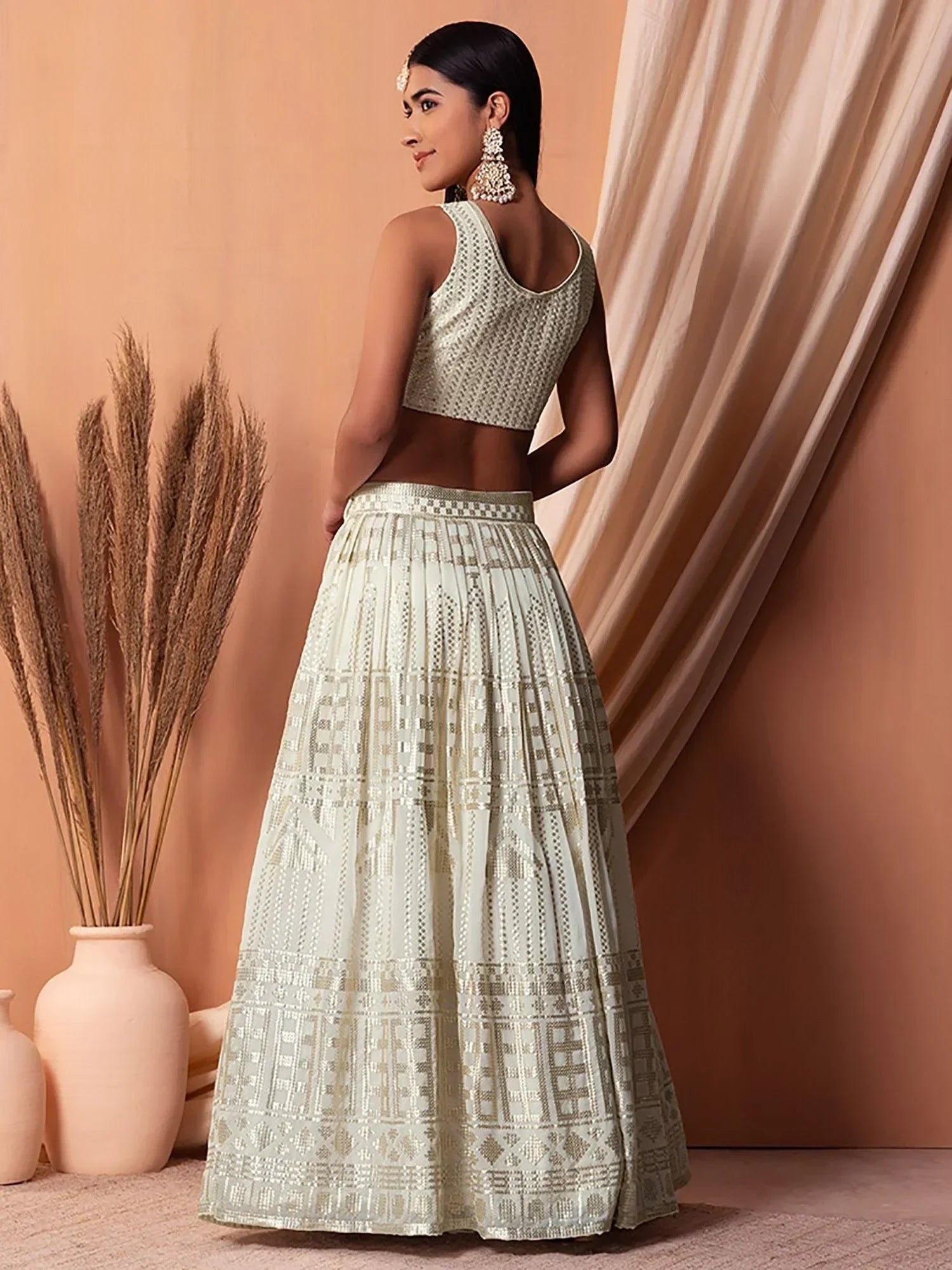 Elegant off-white lehenga choli with gold geometric embroidery, perfect for Indian ethnic wear occasions.