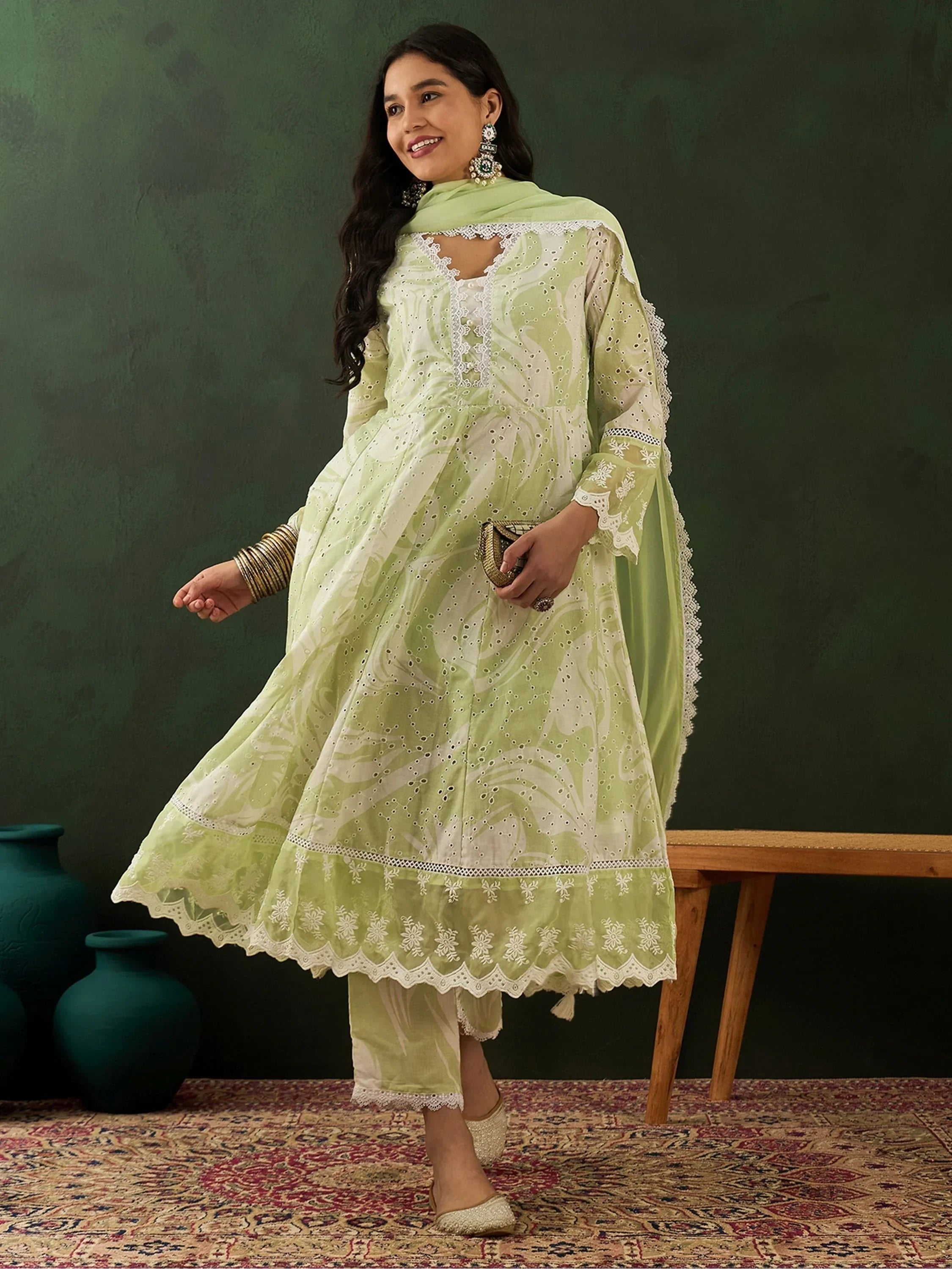 Woman wearing light green embroidered salwar kameez with dupatta, ethnic jewelry, and juttis
