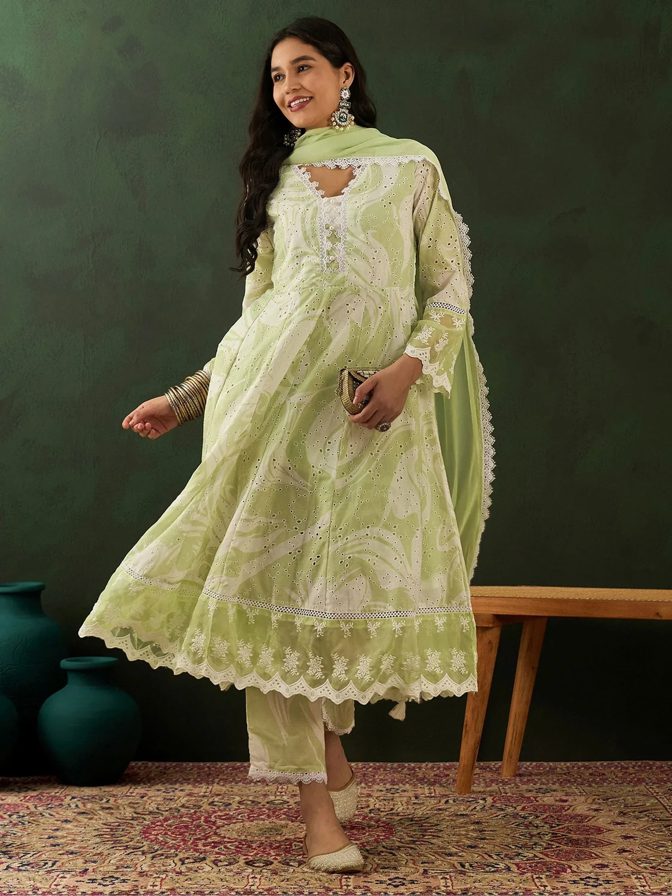 Woman wearing light green embroidered salwar kameez with dupatta, ethnic jewelry, and juttis