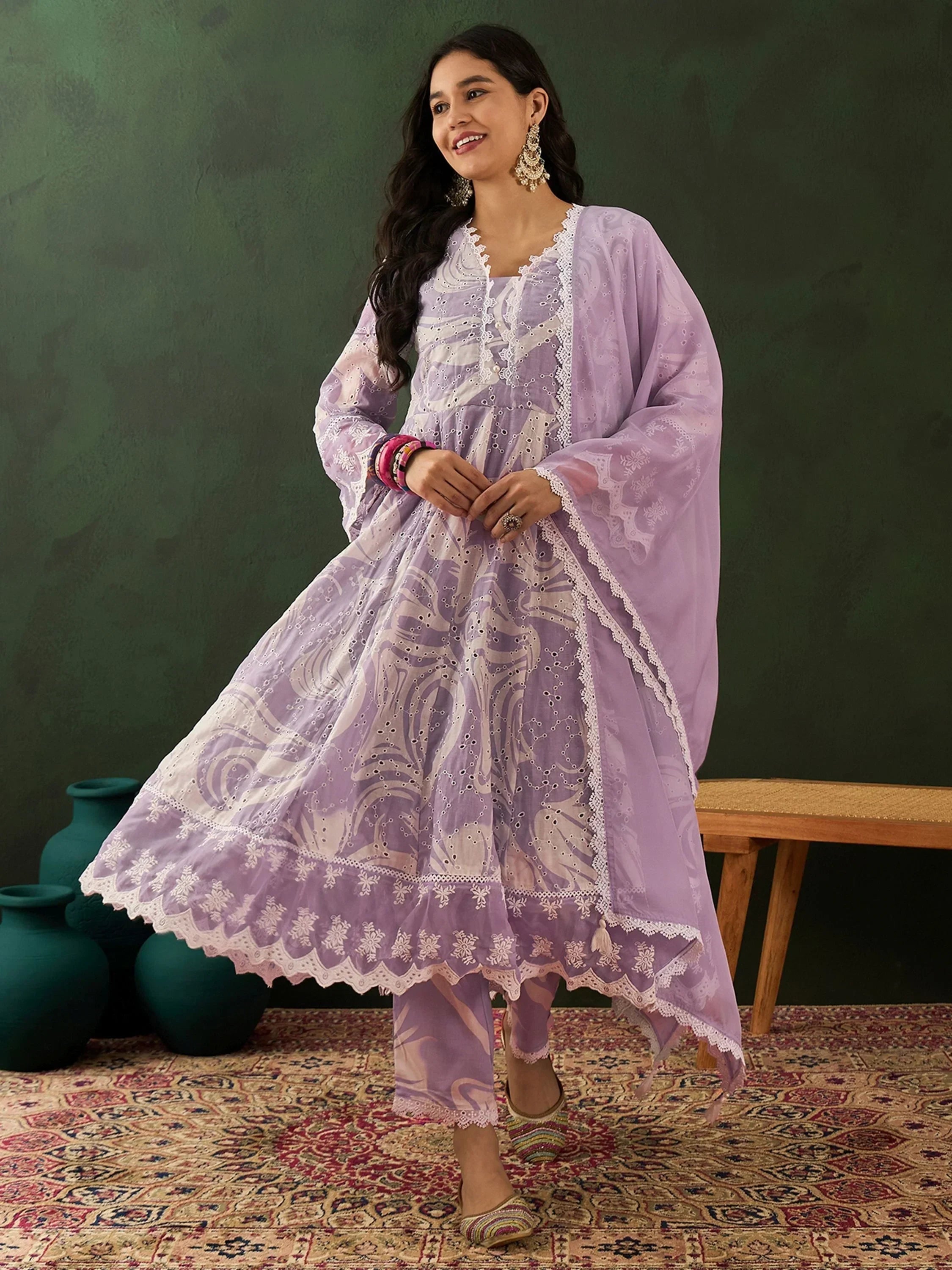 Woman in lavender embroidered salwar kameez with dupatta, posing on patterned rug